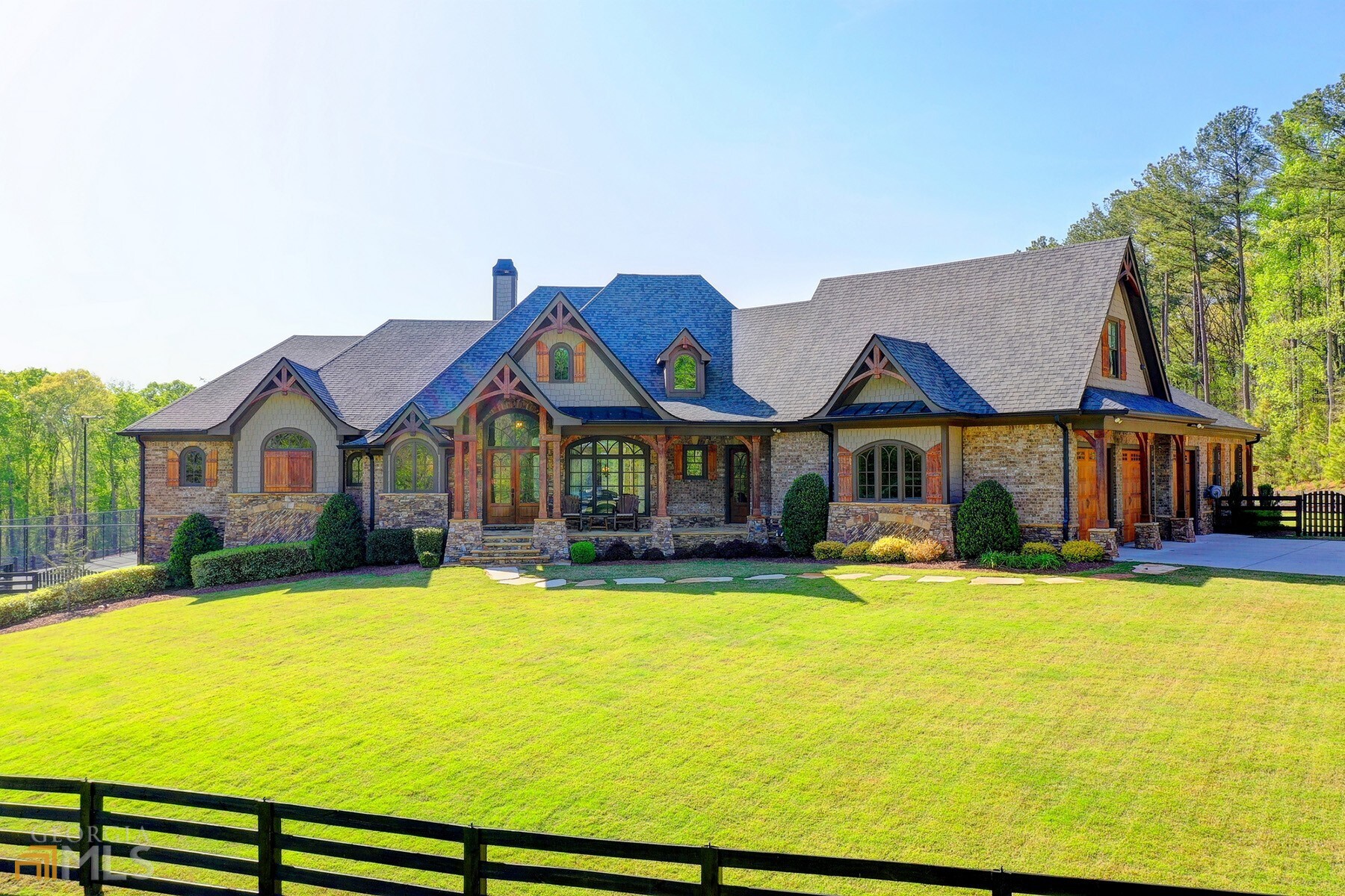 Welcome home to this masterpiece of an equestrian estate. Charm abounds both inside and out of this picturesque property. A privacy gate with a call box welcomes you onto the sprawling, 19+/- acre property while beautifully sculpted landscaping leads you up to the custom-built home. Also situated on this large property is a seven-stall barn, a covered riding arena with Geo-Tex footing, four luscious pastures, gorgeous HORSE TRAILS through out the property, LED-lit tennis and pickleball court, a resort-style pool, a two-bedroom, two-bathroom cabin with a loft and an outdoor riding arena with an overlook pavilion which includes three swing beds, a bar, and a gas fire pit. The entire property is irrigated and has landscape lighting and audio systems throughout, along with a very impressive & extensive Control 4 App system that has power command on the fully wifi estate. Lights on/off , doors locked/ many more options at your fingertips! The detached garage has 4 bays/8 car space for your outdoor needs. Luxury redefined. The stunning, one-of-a-kind home first impresses with the large front porch. Inside, the grand foyer showcases a gorgeous vaulted ceiling and is flanked by the impeccable formal dining room and access to the terrace level. You can't miss the large windows throughout the home that boasts long-range views of the property. Both cozy and spacious, the fireside family room is flooded with natural light and boasts a wood-paneled vaulted ceiling and a massive chandelier. At the heart of the home, find the chef's kitchen with top-of-the-line appliances, gorgeous stone accents, a large kitchen island, a sun-lit breakfast nook and views into the living room with a coffered ceiling. This space is ideal for large gatherings and entertaining. Relax and unwind in the primary suite, ideally nestled on the main level. Some of the incredible features include a beamed ceiling, a stone accent wall, a separate sitting room with built-ins, a truly spa-inspired bathroom and a walk-in closet with its own washer and dryer and shoe nook. A private guest suite is ideally situated on the main floor and has quick access to the pool. Upstairs, four more large bedrooms boast unique details in every corner! Below, the incredible terrace level is sure to impress and make entertaining a breeze. A Full-Swing Pro Series Golf Simulator with a complete sports package awaits along with a nine-seat movie theatre and a two-lane duckpin bowling alley. Also, on this level, find a massive bar, a home gym, a billiards room with an air hockey table and a poker table and a large bedroom with a full bathroom. Outside, enjoy a kitchen bar, a large, serene pool and spa with waterfall features, a fire pit, a screened patio with a fireplace and a swinging couch, a breathtaking horse sculpture and a basketball hoop in the large driveway. This estate could also serve as a sports arena for indoor/outdoor turf football. A canvas to partake as your own. Love to travel? The Gwinnett Airport is less than 6 miles away. Discover true beauty far beyond the ordinary at this spectacular residence.