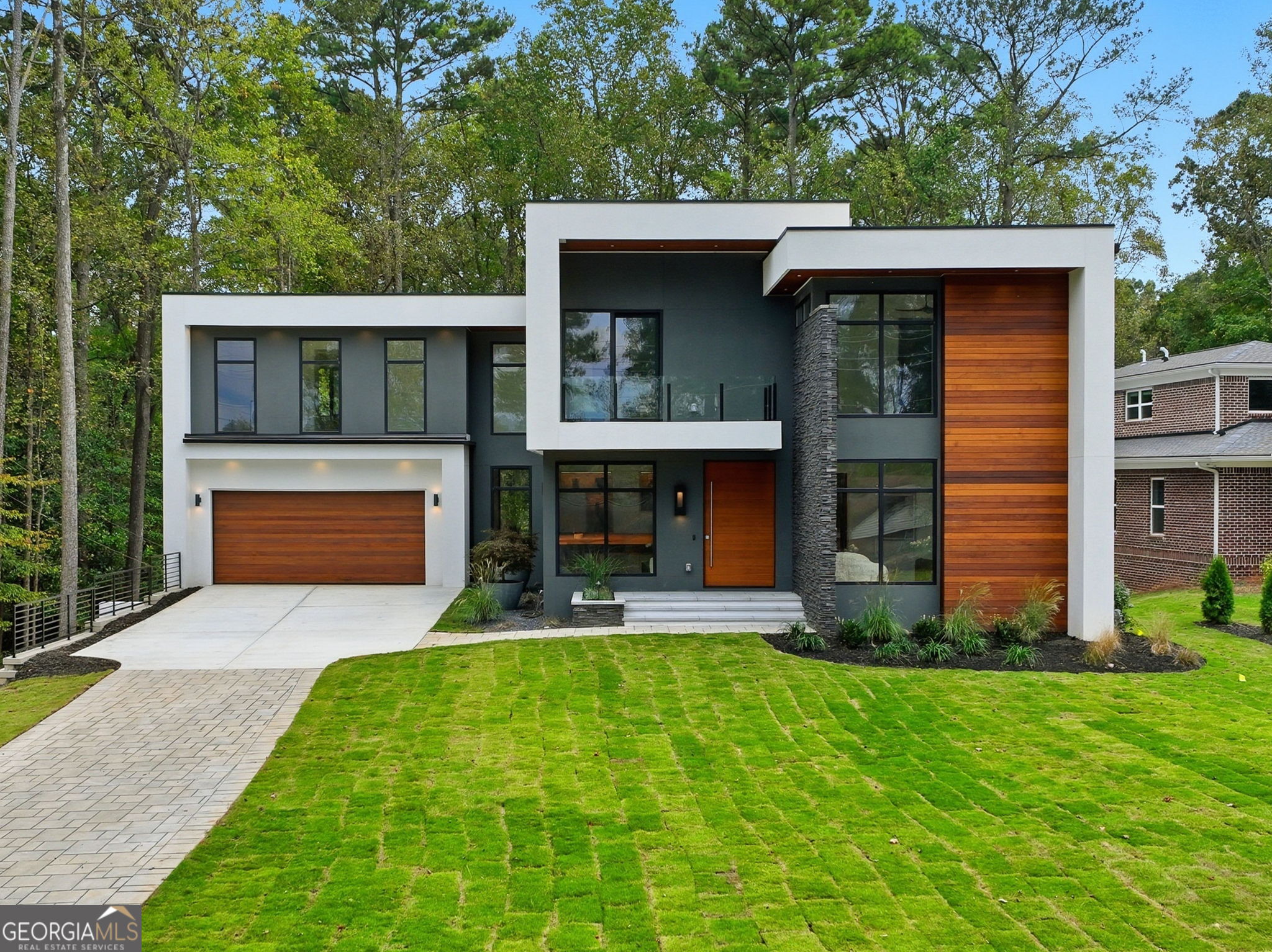 A modern masterpiece redefining luxury living set on nearly an acre of land in one of Atlanta's most desirable locations. Newly constructed modern estate offers the perfect balance of architectural sophistication and everyday livability. Designed with uncompromising craftsmanship, it showcases an extraordinary collection of imported finishes that elevate every space. The dramatic entry begins with a custom solid wood pivot door that opens into soaring interiors flooded with natural light from expansive walls of glass. A floating staircase with sleek cable railing and a fireplace surrounded by a porcelain slab creates a bold yet elegant focal point. At the heart of the home, the chef's kitchen features Wolf and Sub-Zero appliances, European German cabinetry, built in custom kitchen table, a quartz island with integrated lighting, and a concealed walk-in pantry. A wine bar with Taj Mahal quartz and Italian fluted marble backsplash provides the perfect setting for entertaining. Luxury details continue with Brazilian Ipe wood, Italian tile, and custom carpentry throughout. Each bedroom is outfitted with a custom closet, while spa-like bathrooms feature floating vanities, rain shower systems, and imported European finishes. The primary suite is a true retreat with a private balcony, spa-inspired bath, and his-and-her custom closets, while an additional balcony extends from the office for a quiet escape.The finished lower level is designed for entertaining with a second full kitchen, guest suite, and a home theater hidden behind a secret door with custom lighting. Blending indoor and outdoor living, a covered porch with oversized sliding picture window door, frames the exquisite wooded backyard views, offering both privacy and tranquility. All within walking distance to Emory University, CDC and Thompson Park, this modern gem sets a new standard for contemporary luxury in Atlanta.