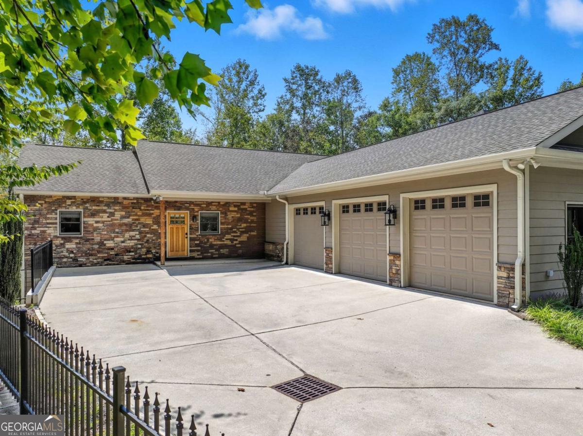 Stunning Lakefront Ranch with Panoramic Views, Private Double-Slip Dock & Party Deck! Welcome to your dream lake retreat! This beautifully designed ranch-style lakefront home offers 3,820 sq ft of finished living space with breathtaking panoramic Lake Lanier views from both levels. Featuring 4 spacious bedrooms, 3 full bathrooms, and a bright open-concept layout, this home is ideal for both everyday living and entertaining. Step inside to enjoy the fresh, modern feel of brand-new flooring throughout and stylish new light fixtures in the entryway, dining room, and kitchen island. The main level includes a luxurious master suite, a large laundry room, and a cozy fireplace-perfect for relaxing evenings. A second fireplace in the lower level adds warmth and charm to the expansive living space below. Outdoor living is exceptional here. The back deck spans the entire length of the house on both levels, providing abundant space to entertain or relax while soaking in the stunning lake views. There is a screened-in porch off the living and dining room features a vaulted ceiling, creating a spacious and airy retreat. Additionally, there are two private decks on the main level-one off the master suite and another off a spare bedroom-offering peaceful, private spots to enjoy the outdoors. Situated on a beautifully landscaped .48-acre lot, the property boasts brand-new landscaping that enhances curb appeal and creates a lush, welcoming atmosphere. A three-car attached garage and abundant storage throughout-including oversized closets, utility rooms, and bonus spaces-provide exceptional functionality. For lake lovers, the private amenities are unbeatable: a private double-slip dock with boat lift, party deck, and a brand-new jet ski included make lake life effortless and fun. Built just six years ago, this move-in-ready home offers modern comforts, timeless design, and unbeatable access to the water. Listed at the recent appraised value - appraisal is available for review on MLS for buyer confidence.