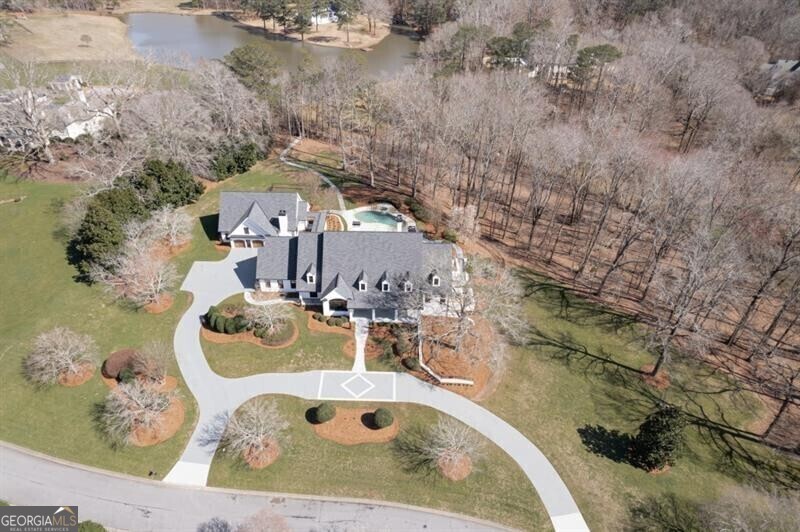 FIVE STARS !! This stunning and private 5+ acre estate is set amongst green rolling land and just a short winding trail away from a dock to your stocked lake. in the middle of Johns Creek. This estate which includes both a MAIN HOUSE and a GUEST HOUSE was designed to take advantage of the abundant natural light and beautiful vistas, and has just completed a TOTAL RENOVATION for both the 10K+ sf main house as well as the 2 bedroom / 2 bathroom guest house accessible via private breezeway. Immerse yourself in the elegance and sophistication of this custom-built, one-of-a-kind masterpiece that now feels like NEW CONSTRUCTION. The front porch welcomes you in and begs you to linger longer. Enter through the double doors to gleaming hardwood floors and a beautiful foyer. The banquet-sized dining room with stunning chandelier can easily seat parties of 12 or more. Work from home in the bright, spacious study. Delight the chef in you with the gourmet kitchen's expansive island, stainless appliances, huge walk-in pantry, gorgeous counters, and stylish accents. The great room with its fireplace and built-in bookcases opens to the keeping room and kitchen. Designed with both comfort and entertainment in mind, this open floor plan is light and bright and also opens to a covered screened porch and sunroom to seamlessly blend inside and outside living. The main level master suite is a haven away from the hustle and bustle of daily life with its vaulted ceiling and fireplace, beautiful spa-like bathroom, huge closet, and bonus room that can be a nursery/mom's office or second closet. The main floor is completed with a full laundry room. Upstairs, discover four secondary bedrooms with adjoining bathrooms, second laundry room, and two bonus rooms that could be a great theatre room, playroom, study room, or crafts room. The terrace level also has great spaces with an entertaining bar, media room, full bedroom with bathroom, sauna, exercise room, and play room PLUS TONS of extra storage space. The huge bonus is the full two bedroom guest house. The backyard is perfection with its beautiful landscaped grounds, azure pool, and nature walks to the lake. So much beautiful nature and the ultimate in PRIVACY but close to everything including top-ranked schools, great shopping, delicious restaurants. PERFECTION!