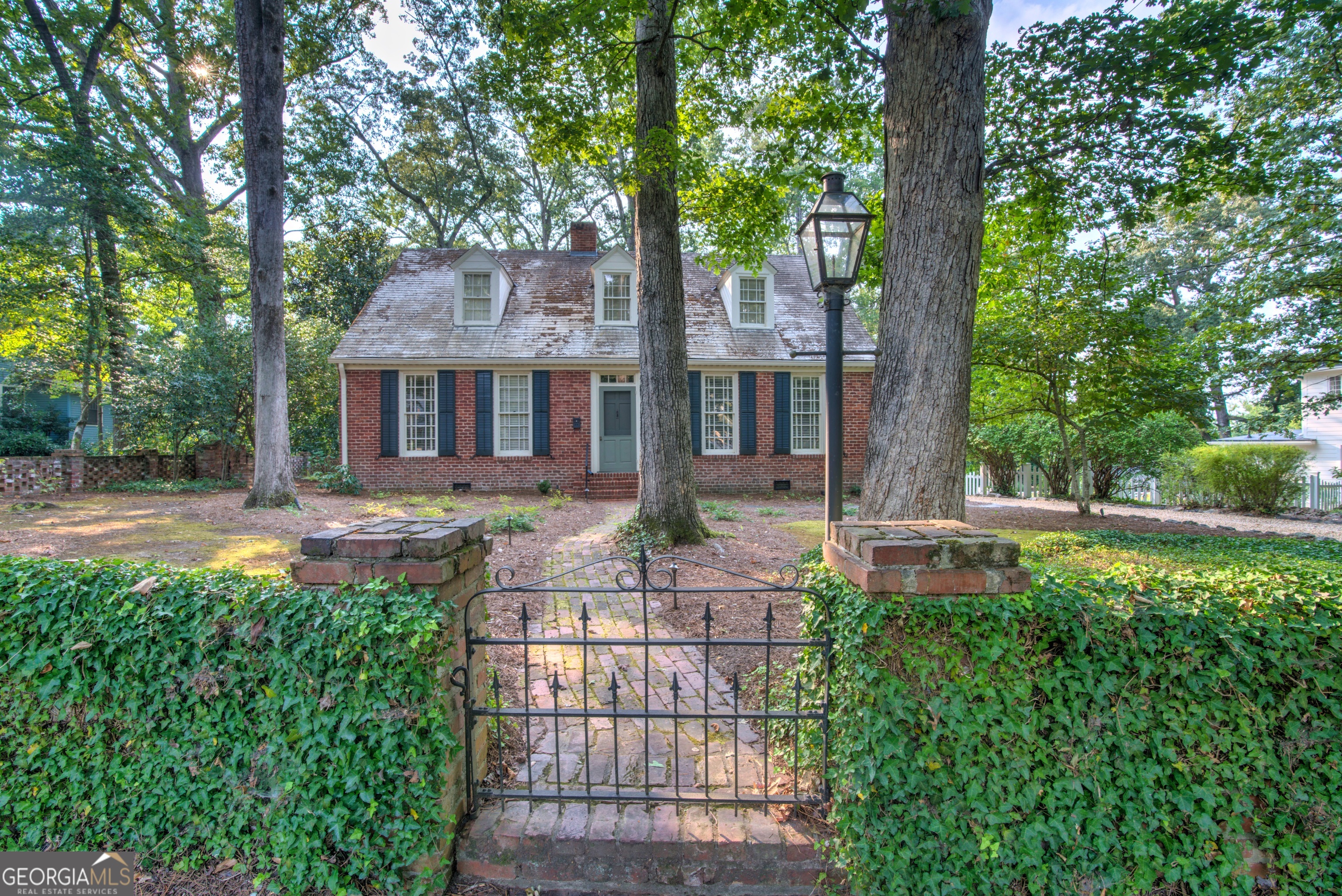Welcome to this enchanting historic home, nestled in the highly sought-after College Heights neighborhood. From the moment you arrive, its timeless charm is undeniable. A brick border draped in ivy sets the stage, while a wrought iron gate and flickering gas lanterns invite you inside. Both the front and back yards are a whimsical dreamscape, complete with mature landscaping and two peaceful water features that create a serene retreat right at home. A detached carport with an attached workshop offers convenience and functionality. Step inside and you'll immediately notice the character-rich details, including wide plank heart pine floors that flow throughout the home, blending warmth and history with modern updates. The kitchen is both beautiful and practical, featuring elegant soapstone countertops, a butcher block island, and ample cabinetry-ideal for both everyday living and entertaining. The primary suite is a true sanctuary. The fully renovated master bathroom boasts a luxurious clawfoot soaking tub, a spacious walk-in closet with custom shelving that maximizes storage. Upstairs, you'll find an additional office space-ideal for working from home or as a quiet retreat. Off the dining room isas well as a sunroom that overlooks the enchanting backyard. Here, you can enjoy year-round views of the lush landscape, complete with meandering paths and tranquil water features that make this property feel like a private garden paradise.