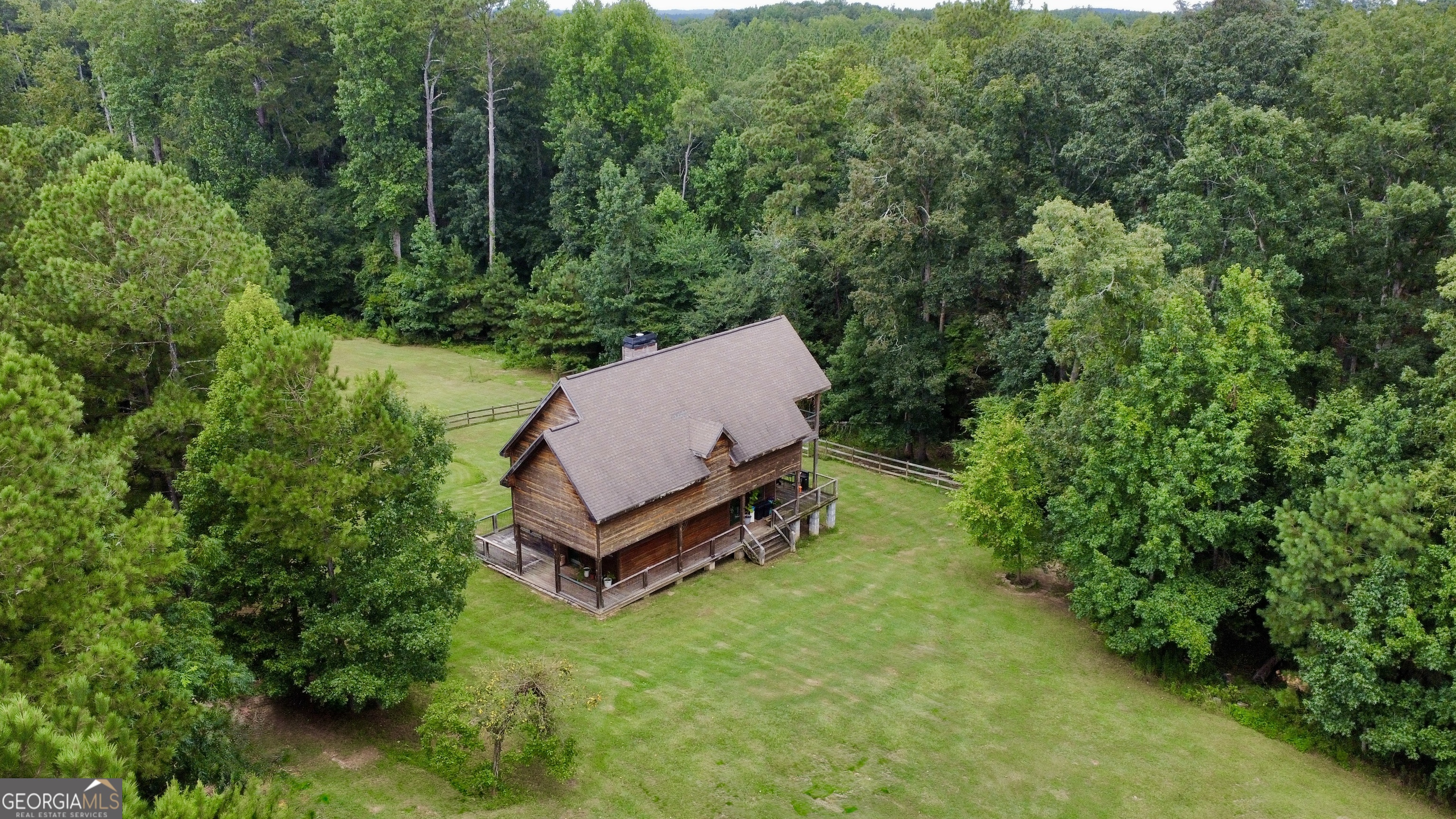 Your Private Country Retreat Awaits! Discover the ultimate combination of privacy, outdoor adventure and rustic charm. A serene 15+acre escape designed for those who crave country living and privacy. A true nature lover's sanctuary. The home feels like a rustic cabin retreat, featuring 3 bedrooms and 3 full bathrooms, an inviting open concept living area with a cozy fireplace and abundant natural light. The kitchen has a new dishwasher, natural wood cabinetry and granite countertops, creating the perfect space to prepare meals after a day spent outdoors. The primary suite offers a private escape with its own balcony overlooking the scenic property. Outside, you'll find fenced pasture areas, ideal for livestock or horses, a creek, along with dense woods that create a hunter's paradise. Wildlife is abundant, and the land offers endless possibilities, add ATV trails, setup deer stands, gardening, or simply enjoying nature and peaceful country living. Another standout feature is the spacious 30x50 metal shop with three roll-up doors, perfect for equipment, vehicles, or hobbies. Additional highlight is the wraparound porch made for sunrise coffee, afternoon tea, quiet evening's and weekend BBQ. With No HOA, plenty of space to roam, and proximity to Lake Oconee and downtown Greensboro, this property is a rare find for those seeking a private country retreat. Call Luvee (404) 698-7910 and schedule your showing today!