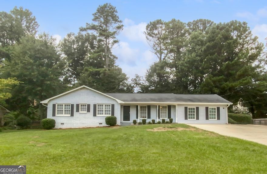 This charming brick ranch, situated in the highly sought-after East Cobb Wheeler School District, offers a welcoming blend of comfort and style. Step inside from the inviting covered front porch to discover a beautifully maintained home with a bright, open floor planCoperfect for entertaining. Gleaming hardwood floors flow seamlessly from the cozy family room, complete with a fireplace, into the sunlit dining area at the heart of the home. The spacious kitchen is a chef's dream, featuring stainless steel appliances, elegant marble countertops, and a custom tile backsplash. Retreat to the private owner's suite, which boasts an ensuite bathroom with a stunning subway tile shower. Two additional bedrooms share a hall bathroom equipped with a double vanity, providing plenty of space for family or guests. The converted garage, featuring a large walk-in closet, offers flexibility as a potential fourth bedroom, bonus room, or home office. Step outside to the tranquil, tree-lined backyard, perfect for relaxing or hosting gatherings. The deck, storage shed, and firepit patio create an ideal outdoor living space. This home is conveniently located just minutes from The Battery, Historic Marietta Square, Chattahoochee River National Park, and offers easy access to I-75. Don't miss this exceptional opportunity to enjoy modern living in a prime location!