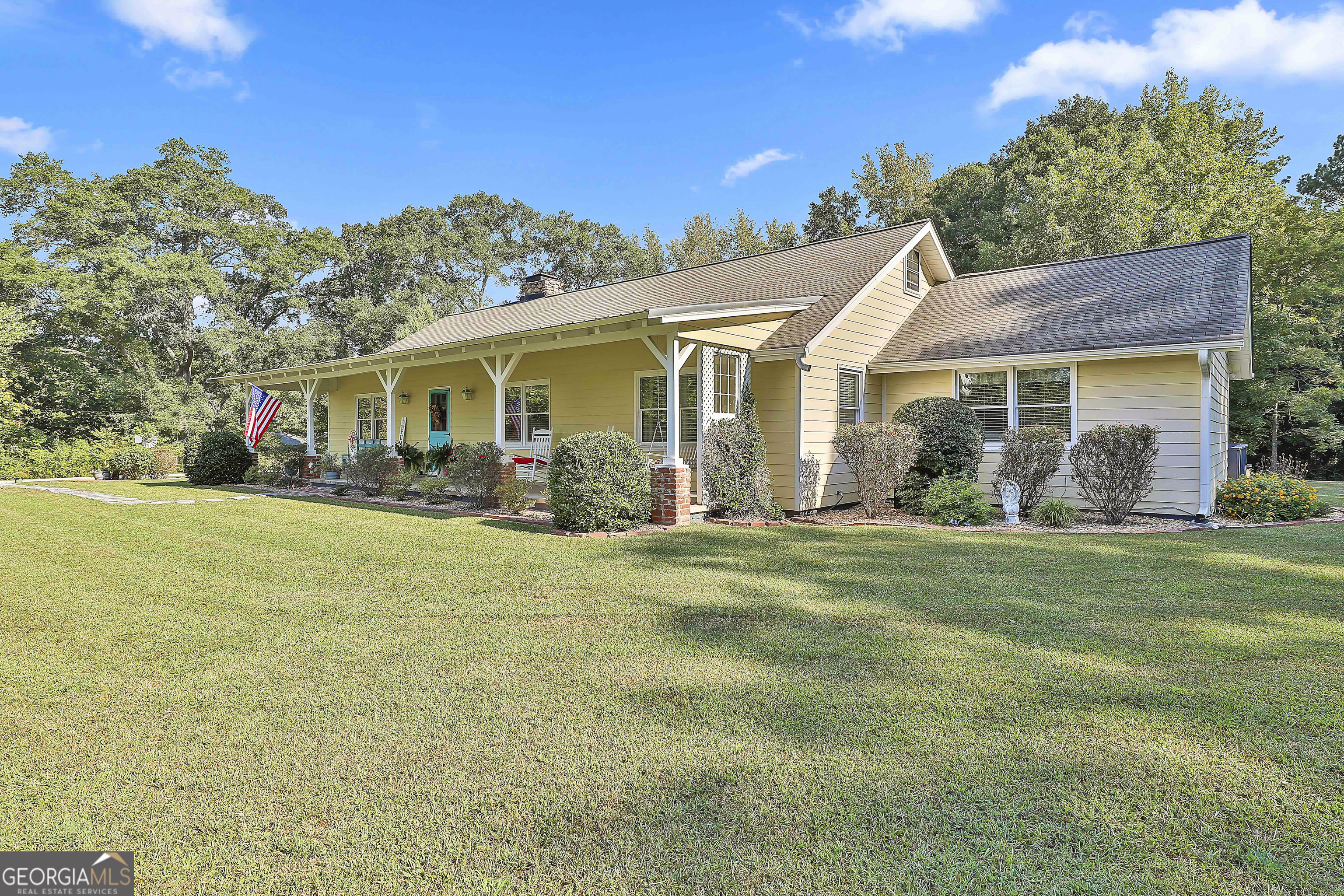 Set on four peaceful acres in Fayetteville, this beautifully updated 1960s farmhouse blends timeless charm with modern comfort. A winding, tree-lined driveway leads you to an expansive rocking-chair front porch and a screened side porch with a classic brick water table-perfect spots to savor quiet mornings or relaxed evenings. Though only 10 minutes from I-85 exit 61 and just 20 minutes to Hartsfield Int'l Airport, the property feels miles away from the bustle of daily life. Inside, the sense of home is immediate. Original hardwood floors, vintage doors with period hardware, and touches of shiplap, beadboard, and custom ceilings honor the home's history, while thoughtful updates provide everyday convenience. The front entry opens to a welcoming living room anchored by a stone masonry fireplace with built-in wood storage. The newly remodeled kitchen pairs custom cabinetry with rain-glass upper doors, leathered granite counters, a farmhouse sink, and a breakfast bar with butcher block top. Stainless appliances, a decorative tile backsplash, and a built-in wine rack complete this gathering space. The kitchen flows easily into a spacious dining area for formal or informal meals where family and friends can gather. Down the hallway, the primary suite features a shiplap accent wall, dual closets, and a reconfigured bath with a large walk-in shower and a private water closet with sink vanity. Three additional bedrooms-one currently used as a home office-offer generous closet space and share a stylishly updated guest bath with a wood-look tile floor, decorative sink vanity, and ceramic tub/shower surround. Just off the kitchen and with a rear entry to the carport, is an informal foyer with shiplap walls that provides a large drop zone with bench seating, dual storage closets, and hooks for coats, hats, etc. with shelving above. Beyond this space, a flexible bonus room invites you to create the perfect game room, studio, or additional family gathering area, and a fixed staircase offers access to abundant floored attic storage. On the opposite side of the back foyer, a sliding barn door opens to a spacious mudroom that includes laundry facilities, pantry shelving, and room for an extra refrigerator or freezer. A full bath with an oversized tiled shower with toilet and sink vanity completes this side of the home. Outdoor living is equally appealing. With the mostly grassy 4 acres, the property could easily be fenced to house a horse or two. A two-car carport adjoins a small shed that houses a large storage tank for well water used in outdoor watering. The fenced area just to the back of the carport and adjacent to the house is ideal for pets, play, or a garden, and the circular drive leads to a 30' x 30' workshop with electricity and an open covered area to the rear that is of pole-barn construction. Situated near the upcoming Arthur M. Blank U.S. Soccer National Training Center, Trilith Studios, and the vibrant Town of Trilith, this property offers a rare combination of privacy and accessibility. With its mix of original character and thoughtful renovations, this Fayetteville farmhouse is more than a house-it's a place to feel at home.