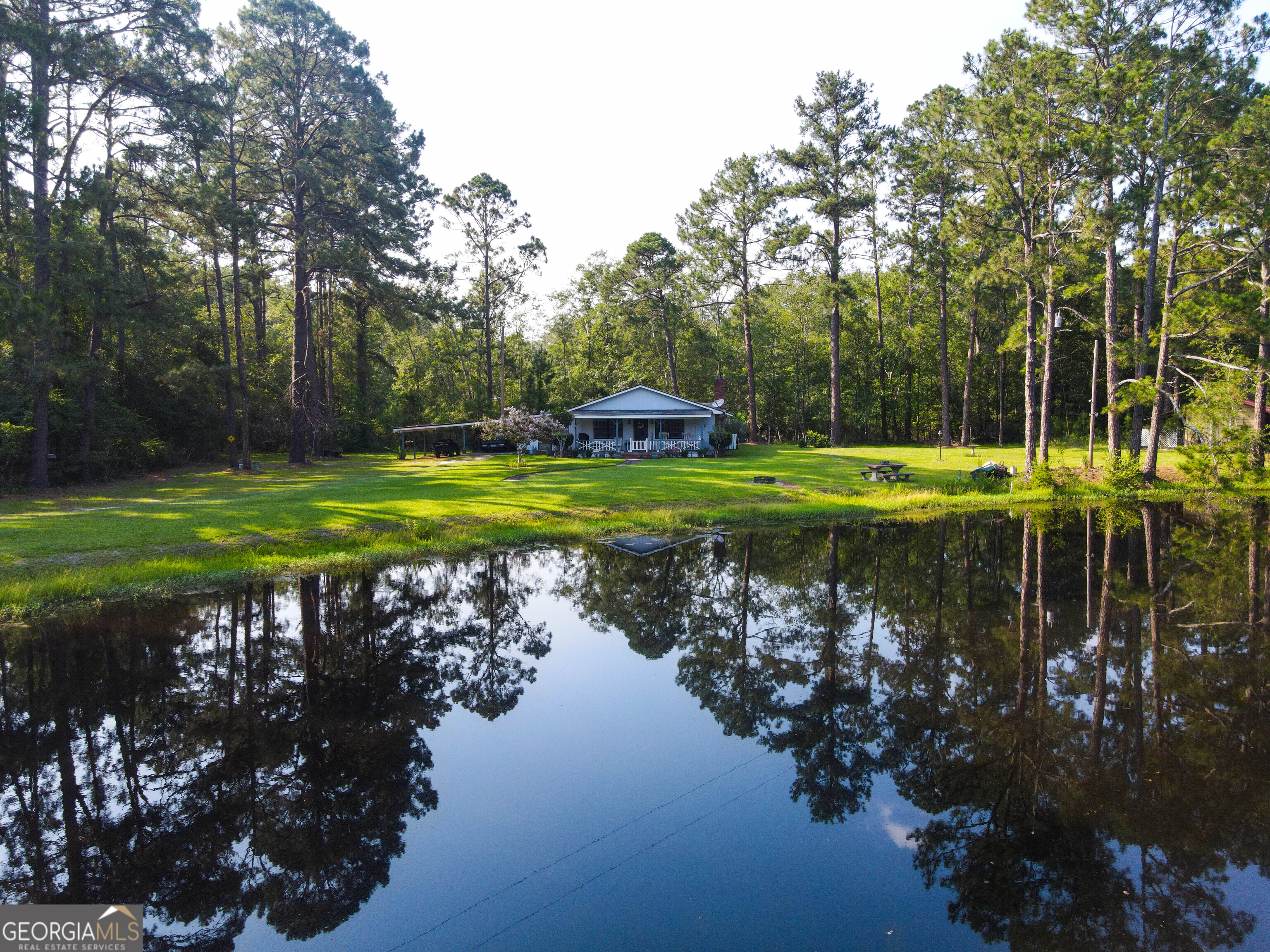 Looking for a quiet, country setting to get away from the noise? Look no further with this beautiful home tucked in a rural, quaint area situated on over 10 acres on the Westside of Bulloch County. The house boasts 1,965 square feet and is on one of the prettiest lots in Bulloch County over looking a beautiful pond. The home itself flows nicely and is very inviting with a vaulted, beamed ceiling. The large open dining room could entertain multiple guests and the living room has a huge fireplace that adds to the rustic feel of the home. The master bedroom has tall ceilings and a huge master closet. There are two storage buildings on the property, both with electricity, giving you ample room for all your tools and toys. Additionally, there is a fishing hut on the pond dam that could hold all of your fishing gear. The pond is stocked with catfish, crappie, bass, and catfish. The amount of wildlife that can be seen around the area is truly remarkable, with deer coming out feeding all times of the day. With no HOA and being tucked back in the woods down a long driveway, come make this slice of heaven yours today! This property is a hidden gem in one of the most desirable areas in Bulloch County. Call for a showing today!