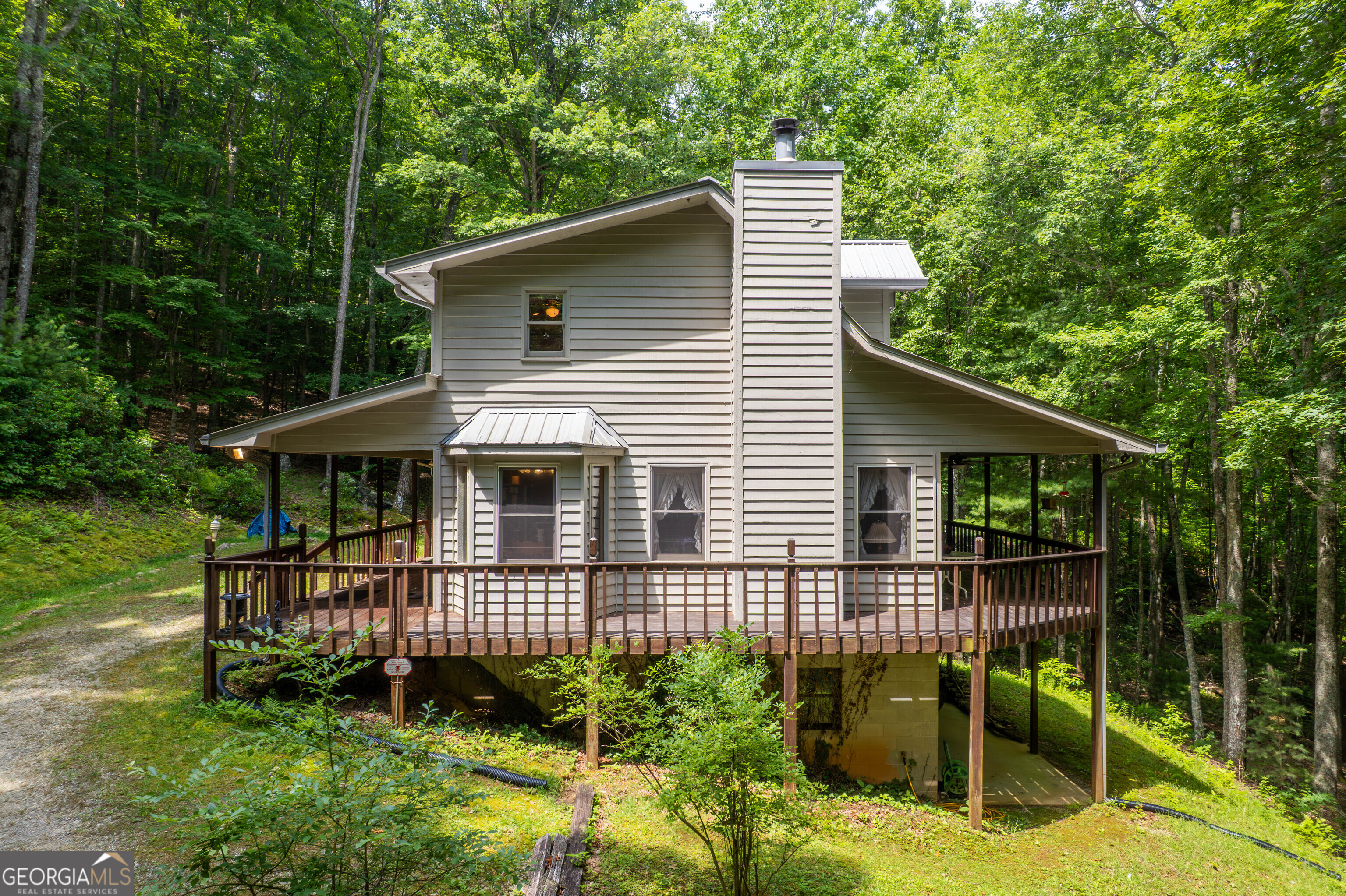Tucked away on a serene 10.1-acre parcel bordering US Forest Service land, this unrestricted mountain retreat offers the ultimate escape without sacrificing connectivity-high-speed internet is available via Windstream! The charming 2-bedroom, 3-bath home features a spacious wraparound porch perfect for morning coffee or evening stargazing. Inside, you'll find a cozy layout with a wood-burning fireplace, bright kitchen, and generous living spaces ideal for gatherings. The full basement provides extra storage or workshop potential. Nature lovers will appreciate the walking trails winding through mature hardwoods, leading directly to the border of USFS land-plus, the headwaters of Reynolds Branch run right through the property, adding the soothing sound of a mountain stream to your backyard adventures. With no restrictions, you're free to live, rent, or build your dreams as you wish. Whether you're craving a private getaway, a homestead, or an investment opportunity, this peaceful haven checks all the boxes. Ready to roam the woods and Zoom from your porch? Let's schedule your showing today!
