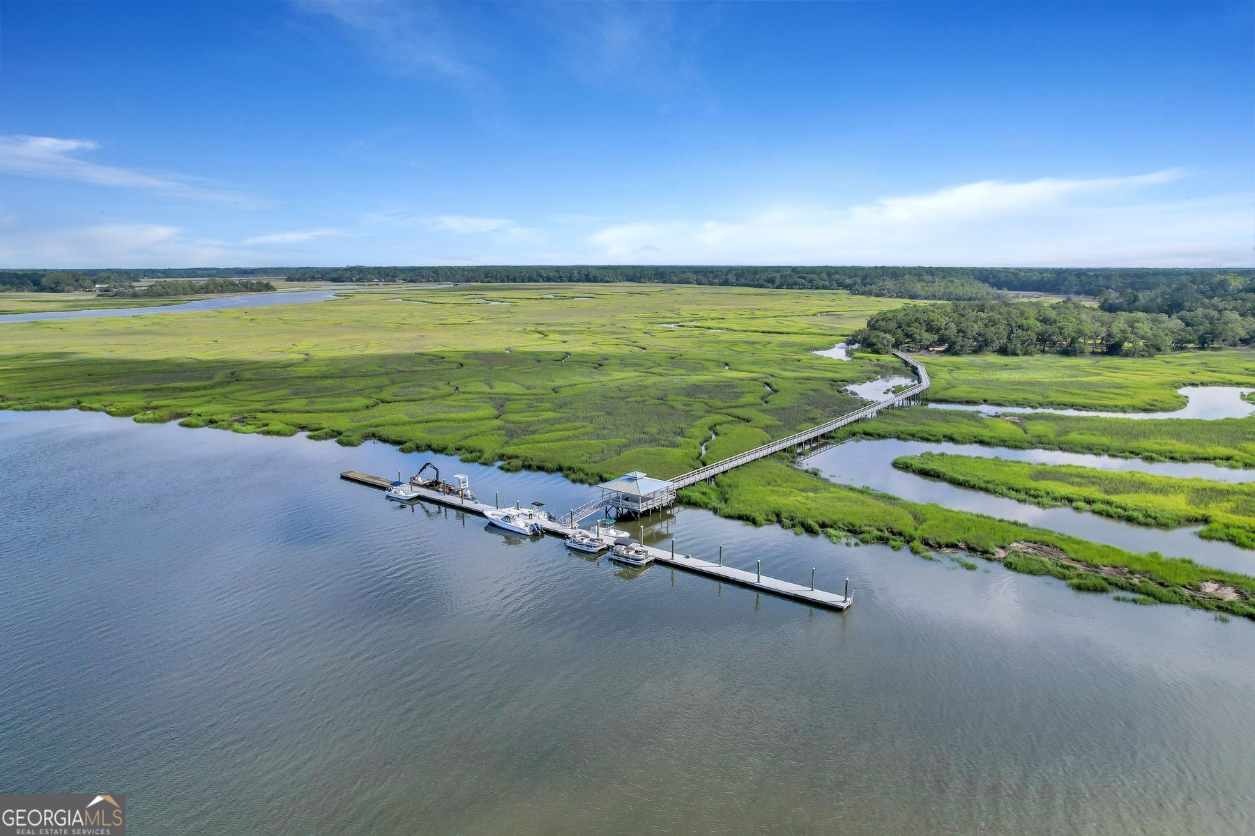 **GATED COMMUNITY**COMMUNITY DEEPWATER DOCK**RV/BOAT STORAGE**FLOOR TO CEILING WINDOWS**TWO KITCHENS** Welcome to Cooper's Point at Shellman Bluff. This charming Lowcountry home blends timeless Southern elegance with modern comfort. Main level features a 2 story great room w/floor to ceiling windows, see through gas fireplace, gourmet kitchen w/granite countertops and stainless steel appliances, primary suite w/ separate sun room, and a spa-like bath with double vanities, oversized jacuzzi tub, and tiled shower. Upstairs are two additional bedrooms, each with ensuite bathrooms and tons of walk in attic storage. The ground level includes a 4-car garage, kitchenette, half bath, and an additional bedroom. Covered front and back porches, plus an open deck and raised garden beds. Community includes gated entry, deepwater dock, 3 pools, 10 ponds, walking trails, tidal creeks for kayaking/canoeing, RV/boat storage, and more. Located next to Sapelo Hammock Golf Club and minutes from the coast.