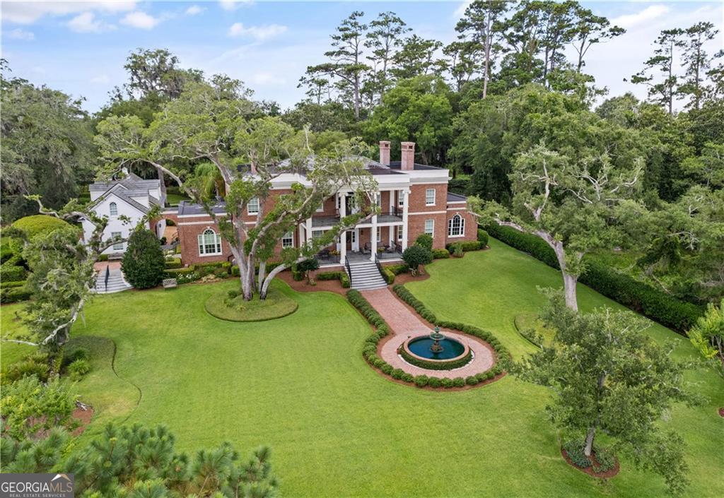 Le Marais is an exquisite example of Georgian architecture, featuring double verandas that offer breathtaking views of the eastern marsh. Appropriately named the marsh in French, Le Marais is inspired by Carter Hall, a historic Virginia estate. This remarkable residence, which has been recognized as an Extraordinary Property of the Day by Sotheby's International Realty, showcases exceptional moldings, fine millwork, and elegant interior design. Inside, the living room boasts a stunning French antique marble fireplace mantel, while the dining room is adorned with a rare 19th-century French chandelier. The marsh-front library/den features intricate moldings, creating a refined space perfect for reading or relaxation. These rooms exude timeless luxury, making them ideal for entertaining or unwinding in comfort. The classic chef's kitchen is designed for both functionality and sophistication, featuring marble countertops, custom cabinetry, and a spacious central island. State-of-the-art appliances include a professional Viking six-burner gas range with warming trays, dual dishwashers, a Sub-Zero refrigerator, and custom sinks. Adjacent to the kitchen, the charming Butler's pantry offers a wine cooler, ice maker, and bar sink for effortless entertaining. The gracious master wing, offering sweeping marsh views, includes a cozy fireplace and separate His-and-Her baths and closets. Two generously sized guest suites, each with en-suite baths, provide privacy and comfort for visitors. An elevator services both floors, while thoughtfully designed storage includes a felt-lined silver closet, a cedar-lined linen closet, and a spacious walk-in pantry. A Generac generator ensures uninterrupted comfort. The three-car garage, styled like a classic carriage house, adds to the home's charm. Above the garage, attached by a charming breezeway,, a private "kid's quarters" serves as a perfect retreat for family or guests. Beyond the home's interiors, the outdoor spaces are equally enchanting. A serene fountain and expansive marsh views create a picturesque setting, ideal for gatherings or quiet reflection. This exceptional home embodies the best of elegant island living, seamlessly blending historic charm with modern amenities in the prestigious, gated community of Hawkins Island, developed by Sea Island.