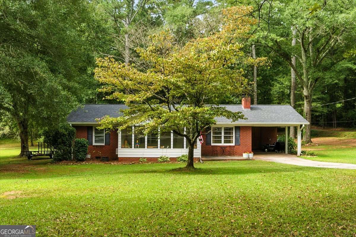 Welcome to this beautifully renovated 4-sided brick country cottage brimming with character and modern upgrades. Nestled on nearly an acre in Carroll County, this 3-bedroom, 1-bath home offers the perfect balance of charm and functionality. Step into the sun-filled kitchen featuring brand-new granite countertops, custom cabinetry, stainless steel appliances, and a spacious island ideal for meal prep or gathering with friends. The open-concept dining area centers around a stunning brick fireplace, creating a cozy atmosphere for entertaining or everyday living. Enjoy abundant natural light from the inviting front sunroom and the warmth of new hardwood-style floors throughout. Additional upgrades include newer roof, HVAC, tankless water heater, and more-ensuring comfort and peace of mind. Outside, the .84-acre lot provides plenty of room for gardening, outdoor living, or simply relaxing in your private backyard retreat. With a car carport and convenient location just minutes from Mount Zion schools, this home truly has it all. Don't miss your chance to own this move-in ready gem-schedule your showing today!