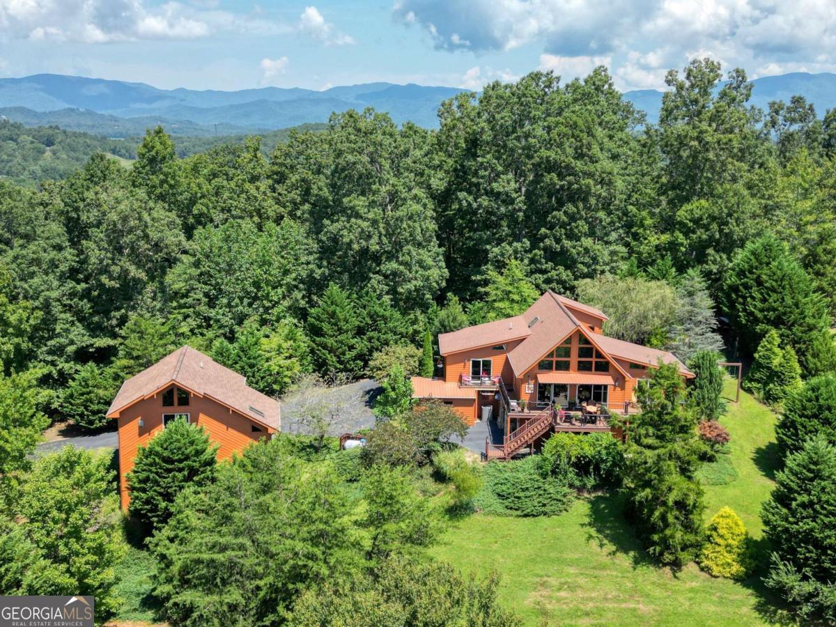 Welcome to 171 Chatuge Shores Overlook - an absolutely stunning turnkey retreat with breathtaking views and luxurious finishes! This exceptional property is a rare gem-offered fully furnished with exquisite, high-end pieces and custom craftsmanship throughout. From the moment you step inside, you'll be captivated by the thoughtful design and elegant flow of this beautifully curated home. The main level boasts an expansive open-concept living, dining, and kitchen area featuring soaring ceilings, a striking stone fireplace, and seamless indoor-outdoor connectivity-perfect for entertaining or cozy evenings by the fire. Just off the main living area is a separate family room, providing an inviting space for more intimate gatherings or relaxation. Each of the three spacious bedrooms is situated on its own level, offering ultimate privacy and comfort, and each comes with a luxurious en-suite bath showcasing beautiful finishes and timeless design. The lower level is designed for leisure and entertainment, featuring a state-of-the-art home theater and a dedicated wine tasting room-ideal for hosting or unwinding in style. Additional highlights include an attached two-car garage at the main residence, with an additional detached two-car garage with a beautifully finished upper-level flex space-perfect for a guest suite, studio, home office, or creative retreat. Outdoor living is equally impressive, with multiple levels of open and covered decks that invite you to take in the panoramic views of the mountains, lake, and golf course. The landscaped grounds offer tranquil sitting areas, a cozy fire pit, and plenty of space to enjoy the serene surroundings. This is more than just a home-it's a lifestyle. With unmatched views, luxurious finishes, and turn-key ease, this property is the total package. Don't miss your opportunity to own this extraordinary mountain retreat.