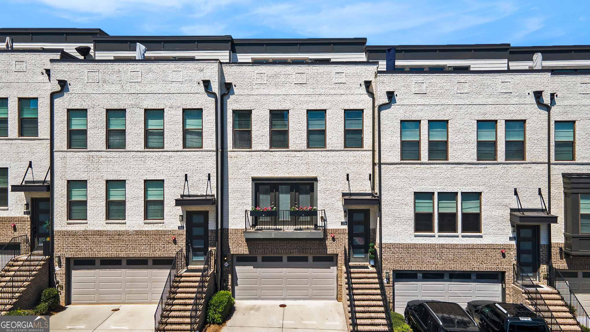 Stunning Contemporary Townhome with Panoramic Skyline Views and Exceptional Upgrades! Experience luxury living with breathtaking skyline views of both Buckhead & Downtown Atlanta-all while enjoying the peace & privacy of a well-situated neighborhood away from the city's hustle. This extraordinary 3-bedroom (possibly 4), 3-full bath and 2-half bath townhome spans multiple levels of beautifully designed space, offering five private outdoor living areas, including 2 rooftop terraces that provide the ultimate backdrop for entertaining, relaxing or simply taking in the beauty of the city skyline & surrounding area. From the moment you enter, it's clear this home has been thoughtfully upgraded beyond builder-grade standards. A welcoming foyer with custom staircase paneling sets the tone, flowing seamlessly into the open-concept main living level. The heart of the home is an immaculate chef's kitchen designed for both function & style. You'll find extended white cabinetry with glass display uppers, under-cabinet lighting, a built-in wine cooler, and a stunning oversized quartz waterfall island illuminated by designer pendant lighting. Premium KitchenAid stainless steel appliances complete the space, including a built-in convection microwave, wall oven, gas range with vent hood, & a French door refrigerator. Adjacent to the kitchen, the spacious family room is anchored by a ventless gas log fireplace, flanked by custom built-in shelving for both storage and display. Tucked just off the living space is a versatile office nook, which leads into an enclosed sunroom-ideal for a peaceful reading space, home office, or play area. Step outside to a covered deck, perfect for morning coffee or evening cocktails. Upstairs, the primary suite offers a serene retreat with elegant tray ceilings, recessed lighting, and dual custom ELFA walk-in closets. The spa-inspired ensuite bathroom features a soaking tub, an oversized glass-enclosed shower with designer tile, dual vanities with built-in cabinetry, and chic matte black hardware. A private balcony off the primary suite adds yet another opportunity to enjoy fresh air and city views. Two additional bedrooms, each with ample closet space, share a well-appointed full bath with floor-to-ceiling tile and modern finishes. A dedicated laundry room with built-in cabinetry completes the level for convenience. Ascend to the top floor entertainer's loft, a flexible space perfect for a media room, second office, home gym, or lounge. A custom butler's pantry with beverage cooler makes entertaining easy. From here, step out to dual rooftop terraces finished with wood decking tiles and turf, providing an elevated experience for outdoor dining, grilling, sunbathing, or hosting unforgettable gatherings against the backdrop of Atlanta's skyline. The lower level adds incredible flexibility with a full private bathroom, a custom closet, and an additional oversized closet for storage, this space is perfect for guests, an in-law suite, or even a quiet home gym or creative studio. The possibilities are endless. Additional features include: 10' ceilings and wide-plank hardwood flooring throughout the main and upper levels, Thoughtful lighting and window treatments throughout, Oversized garage with storage nook, Energy-efficient systems and low-maintenance exterior finishes. Perfectly located with easy access to I-75 and I-285, this home is just minutes from Vinings, The Battery Atlanta, Truist Park, Silver Comet Trail, and numerous dining and retail destinations. Commuting to Buckhead, Midtown, or Hartsfield-Jackson International Airport is a breeze, making this the ideal home for those seeking both luxury and convenience. Don't miss the opportunity to make this spectacular skyline sanctuary your next home!