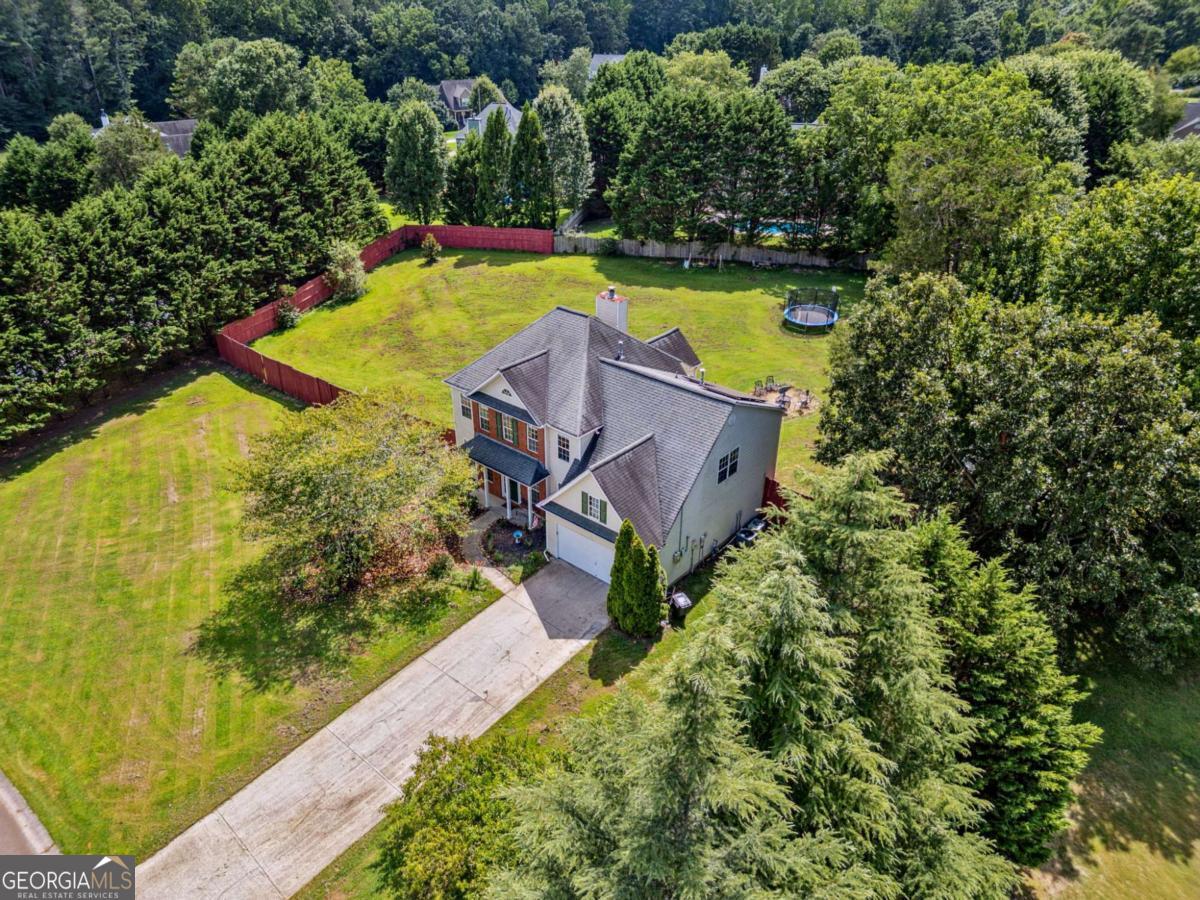 This home is not only move-in ready but is also equipped with energy-saving solar panels! This 5-bedroom, 3-bath home is nestled on just under an acre in the sought-after Holly Trace neighborhood. This spacious home is designed with you in mind, offering flexible living spaces, a fenced yard, and the added value of solar panels for reduced utility costs and sustainable living. Inside, you'll find fresh interior paint in many of the rooms and a functional layout featuring a large family room with fireplace, a separate dining room, and a bonus room on the main-perfect for a guest suite, home office, or playroom. The kitchen offers plenty of cabinet space, a breakfast area, and a view of the family room, ideal for both busy mornings and evening gatherings. Upstairs, the oversized primary suite includes a walk-in closet and a private bath with double vanities. Three additional bedrooms and a full bath, also upstairs, are all good-sized. Outside, enjoy a level, fenced backyard that's ready to be enjoyed by all, plus a powered outbuilding for extra storage or workshop use. With a 9-year-old roof, low HOA, and an ideal location just minutes from Canton, Cumming, and Milton, this home delivers both convenience and value. Move-in ready, family-friendly, and equipped with solar power -don't miss your chance to make this Ball Ground gem your next home.