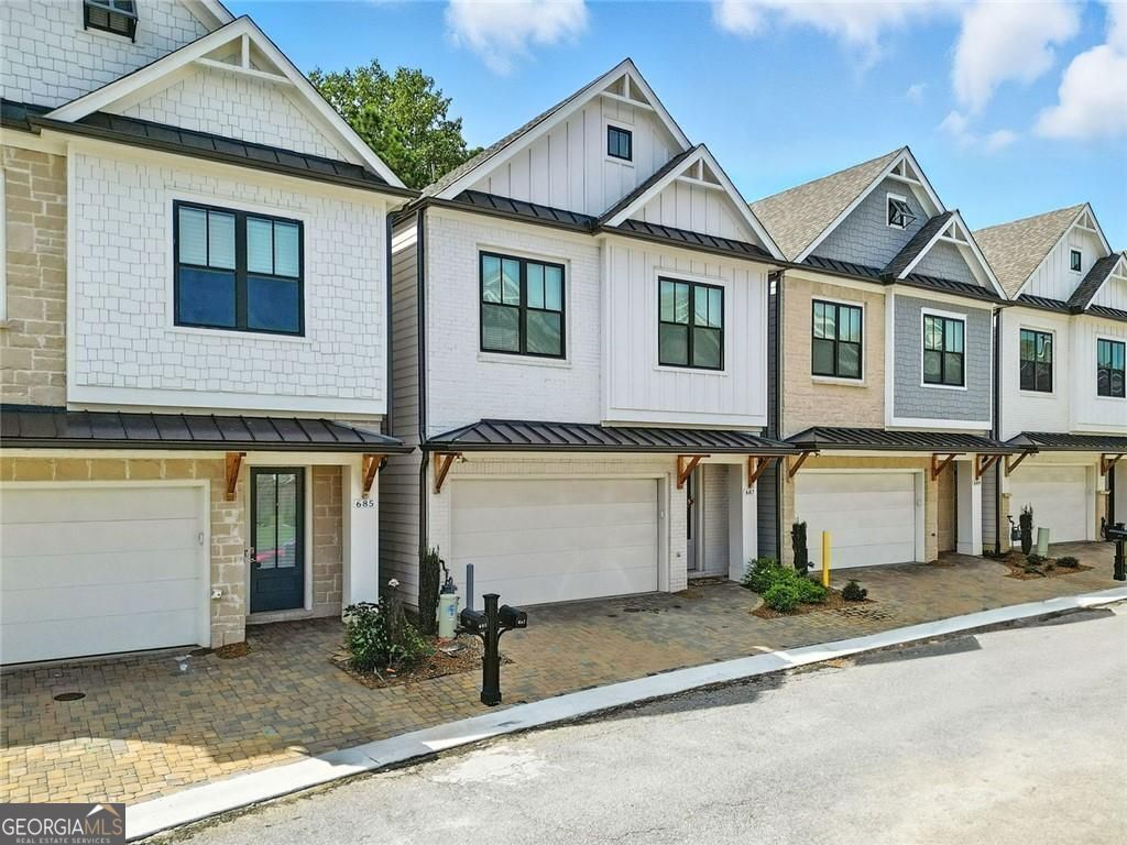 Get a 1/0 rate buy-down for the first year using the Seller's preferred lender! Built in 2023, this clean-lined, modern home delivers standout features from the start. The exterior combines vertical board-and-batten siding, black-trim windows, and natural wood accents that bring warmth and character. Inside, the open-concept layout is bright, functional, and ready for both everyday life and entertaining. At the center of it all, the kitchen makes a strong impression, featuring quartz countertops, a large island with seating, soft-close white cabinetry, and a stainless steel gas cooktop with a statement vent hood. A walk-in pantry, built-in wall oven, and under-cabinet lighting complete the polished look. The open living and dining areas flow together with high ceilings and hardwood floors throughout. Just out back, enjoy two outdoor living options: a ground-level patio perfect for grilling and a private upper deck with access directly from the primary suite. The primary bedroom retreat includes a spa-style bath with a large walk-in shower, double vanity, and a spacious walk-in closet with built-in shelving and storage, keeping everything organized and easy to access. Upstairs offers two more bedrooms, a full bath, and laundry, all tucked into a well-planned layout. Located in a gated community with amenities that include a pool, clubhouse with gym, fire pit, tennis/pickleball courts and three dog parks within the gated areas. Just minutes to Downtown Woodstock's shops, restaurants, and local events.
