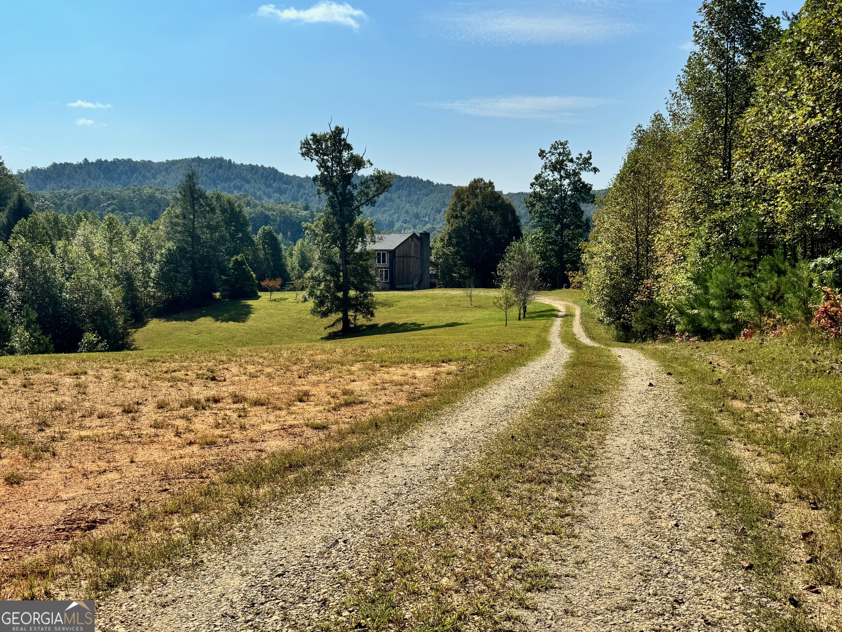 Discover this incredible opportunity to own 12.56 unrestricted acres in the heart of the Blue Ridge Mountains. This scenic property offers a diverse landscape with rolling pastures, fruit trees, wooded areas, and creek frontage-the perfect canvas for your vision of mountain living. Freshly pressure-washed! Whether you're dreaming of a private family compound, working farm, or income-producing vacation rentals, this "fixer-upper" property offers endless possibilities. The existing home, while in need of TLC, is full of charm and potential, featuring wood ceilings and accent walls, and an open-concept living space that invites gatherings and cozy evenings. The main level includes a spacious great room framed by balconies, a large kitchen and dining area, a full bath (with potential for a laundry conversion), and a flex room ideal as an office or extra bedroom. Upstairs, you'll find a guest bedroom with full bath, a large bonus/flex room, and an expansive master suite-all accessible via charming interior balconies that overlook the main living area. The full, stubbed basement includes partially finished rooms, a workshop, and laundry area-offering additional space and flexibility. Covered decks on two sides of the home provide space to relax and enjoy the peaceful setting. With selective clearing, gorgeous mountain views are possible. Recent improvements include a brand-new roof (June 2025) and freshly cut pastures. The interior has been cleaned and is ready for your personal touch. This is a prime opportunity for investors, builders, or visionary homeowners looking to create something truly amazing in the Blue Ridge Mountains. Convenient to Blue Ridge, McCaysville, and Murphy (NC) for hiking, boating, trout fishing, tubing & kayaking, wineries/vineyards and close to unique shopping and dining experiences!