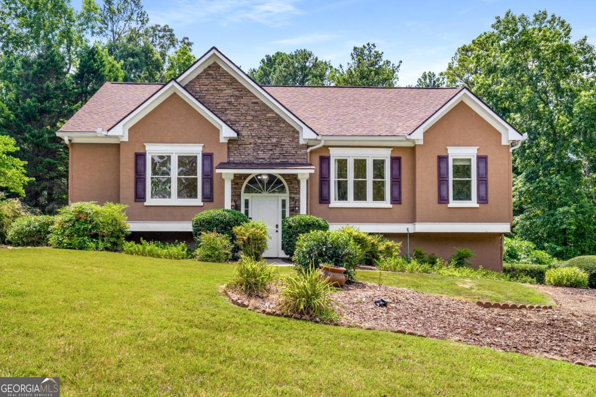 Welcome to this beautifully maintained home on a large, private lot in a quiet, friendly community just minutes from I-575, Downtown Woodstock, and The Outlet Shoppes. With hardwood floors, abundant natural light, and generous gathering spaces, this home blends everyday comfort with easy entertaining. At its heart is a true chef's dream with two full kitchens on the main level-one with white cabinetry, the other with custom-stained wood-plus a breakfast bar, cozy eat-in nook, and view into the family room. Upstairs, the oversized primary suite features dual vanities, a whirlpool tub, and separate shower, while additional bedrooms offer excellent closet space and flexible rooms perfect for a home office, media space, or creative studio. Upstairs, a sunroom bathed in natural light provides the perfect spot for morning coffee, quiet reading, or a cozy second living space. The daylight basement serves as a full in-law suite with a private exterior entry, in-home sauna, and an oversized laundry room with space for side-by-side units, folding tables, and built-in storage, plus abundant additional storage throughout. The garage includes two finished rooms-a dedicated home gym and a separate workshop-offering space for projects and wellness without sacrificing parking. Enjoy peace of mind with a newer roof (2021) and relax in your massive, private backyard ideal for entertaining, gardening, or simply enjoying the outdoors. Thoughtfully designed and move-in ready, this home offers comfort, space, and convenience in one of Cherokee County's most desirable locations.