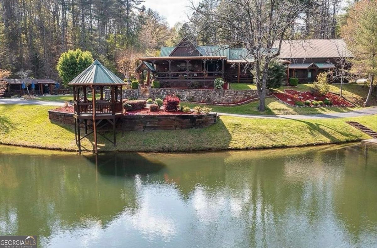 Private Forest Lake in Blue Ridge area : Part of owner/ builders legacy is passing on the preserved integrity of this Authentic cabin! Attention to detail is noticed throughout ! Long winding driveway from the electronic gate w/ view of 8 +- acre lake. Relaxing gazebo at lakes edge, perfect fishing spot or place to read & enjoy total tranquility . Wraparound covered porches & rustic interior offers a cozy atmosphere w/a living & breakfast room off the step-saver kitchen. There's 2 master suites w back-to-back & floor to ceiling stone fireplaces & 2 Bath . This total 11.02 Acres is a haven type retreat a "rare find property" and set away from the chaos of today's busy life , yet accessible to the quaint mountain towns of Blue Ridge, McCaysville, & Murphy, North Carolina. For collectors, hobbyist or other , there's multi-purposed buildings, which must be seen to appreciate & can be utilized for guest quarters/ gathering places or storing prized possessions etc. Lots to do here & explore! Added bonus is a weathered antique barn w/ loft! The renovated corn crib is bursting with personality and is now a treasured picnic outdoor cooking pavilion & overlooks a fresh mountain spring fed koi pond. Also, this land is set up for several r.v. sites--- company can stay awhile! There's 2 private gated entrances & on top of these amenities there's access to the famous & busy Toccoa River. NOTES: certified appraisal can be furnished upon request . ~check out adjacent listing 416001