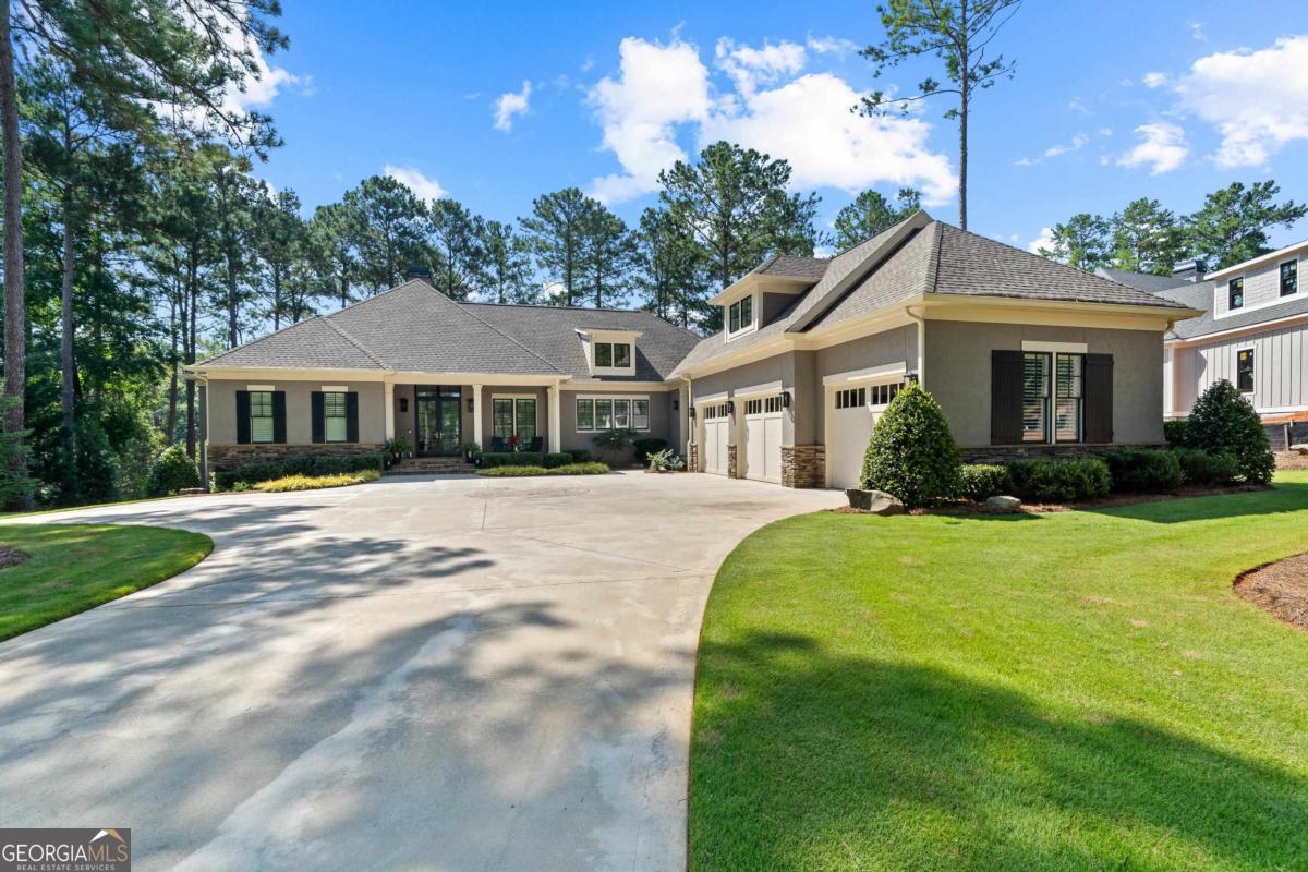 Welcome to this stunning home on the Oconee golf course, offering beautiful creek views. Spanning nearly 6,000 sq. ft., this residence has it all. Upon entry the dramatic foyer, highlighted by a glass-panel staircase, opens to a vaulted great room with shiplap walls and a stone fireplace. The gourmet kitchen boasts stainless steel appliances, marble countertops, custom built-in China cabinet and a center island, flowing into the adjacent dining area and a cozy conversation room-ideal for entertaining or relaxing. Upstairs, a newly finished en-suite over the garage provides outstanding flexibility for guests, a home office, or creative space. The lower level is a haven for recreation and includes a new state-of-the-art golf studio, stylish bar, and three additional bedrooms. Enjoy exceptional indoor-outdoor living with expansive upper and lower porches, outfitted with automatic screens and vinyl panels for year-round enjoyment. Expansive Pella windows with special UV treated glass provide maximum insulation when capturing the natural beauty and golf course views, while multiple living areas ensure comfort and versatility. This home is filled with thoughtful upgrades and special features-too many to list-making it a perfect retreat for those seeking both luxury and tranquility.