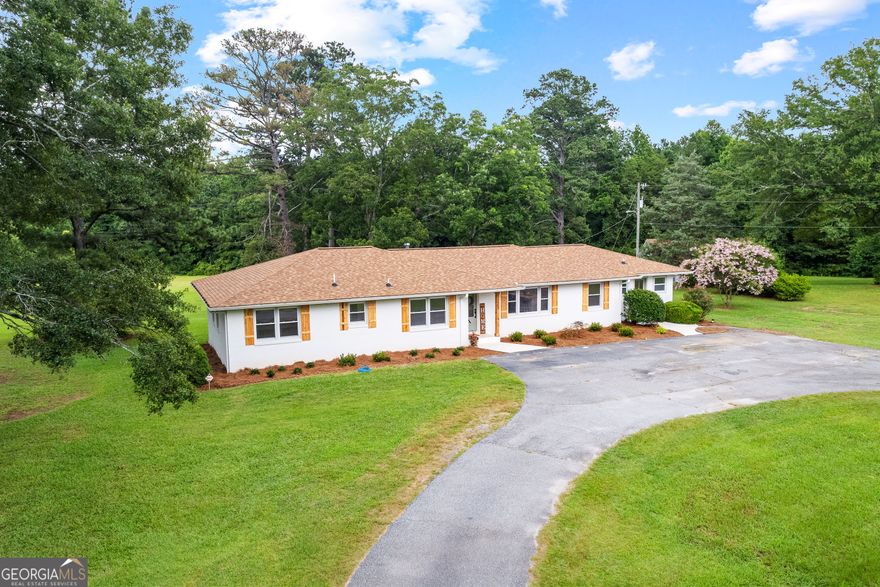 Beautifully remodeled 4-sided brick ranch on 5 private acres in Coweta County! This 3 bed, 2.5 bath home offers the perfect blend of classic charm and modern upgrades. Step inside to an open-concept great room with a stunning kitchen featuring a large island, soft-close cabinetry, all-new appliances, and extra shelving. Around the corner, you will find a walk-in pantry with pull-out shelving. The spacious mud/laundry room includes two side entrances, additional cabinetry, and tons of storage. Relax outdoors on the expansive back deck surrounded by mature trees, perfect for your morning coffee or evening unwind. Unfinished daylight basement provides future expansion potential. A detached 20x40 garage (built in 2000) offers power on a separate meter, a large floored upper-level loft area, and endless possibilities-ideal for a workshop, studio, or guest space. Roof is only 3 years old. Truly a rare find with space, privacy, and thoughtful updates throughout!