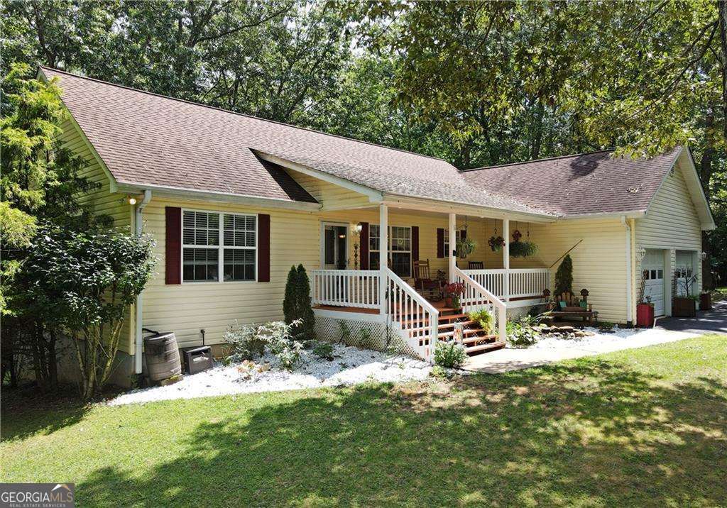 This ranch-style home blends contemporary charm with comfort. The great room features a cathedral ceiling, hardwood floors, recessed lighting, and a gas log fireplace. Enjoy the outdoors with a screened porch and an additional open deck overlooking the woods. The main-level master suite includes a large walk-in shower, soaking tub, and temperature-controlled tiled flooring. The finished terrace level offers a rec room, private office with fiber optic, bedroom and bath, plus an extra-large storage room with shelves. Additional highlights include a rocking chair front porch, greenhouse, and shed. The property is well-maintained and updated, with a private community boat ramp and deeded lake access. No restrictions for storing boats or RVs, with plenty of space on the extra-wide, paved circular driveway. Two-car garage and fiber optic installed.