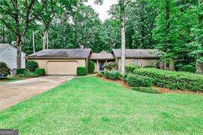 Amazing opportunity in Chimney Springs, one of East Cobb's most sought-after communities! This large ranch-style home is situated in the heart of the neighborhood on a private lot adjacent to the bike and walking path which leads to Chimney Lake and neighborhood amenities. Ready for you to immediately make it your own, or live in as-is and personalize over time! Walking in the front door, you are greeted with beautiful hardwood floors overlooking an expansive living room with vaulted ceiling and stone fireplace as the centerpiece, an adjacent wet bar, and dual sliding glass doors leading to the back deck. The separate dining room connects to the living room for seamless entertaining and features board and batten and a modern light fixture. The spacious eat-in kitchen and breakfast area with updated light fixtures and beadboard wainscoting provide views of the private backyard through sliding glass doors, allowing access to the oversized deck, perfect for relaxing with your morning cup of coffee or grilling in the evenings while entertaining friends! Laundry room with sink connects the garage to the kitchen, creating an ideal drop spot and mud room. The primary suite has a vaulted ceiling with wood beam accent, two spacious closets and ensuite bathroom with recently updated shower. Two additional bedrooms and additional full bathroom complete the main level. The terrace level basement has two large finished rooms ideal for a workout space, home office or playroom and two additional unfinished rooms for storage or an opportunity for you to finish as your own. This is an as-is sale; interior painted 2025, exterior painted 2021, newer HVAC system and newer water heater. Chimney Springs is a very social and amenity-rich neighborhood. Take the trail adjacent to the home and enjoy the swimming pool, clubhouse, tennis and pickle ball courts, lake with bike and walking path, playgrounds, basketball court and activity field. Zoned for top-rated Pope High School, Hightower Trail Middle and Tritt Elementary. This Chimney Springs home is situated within minutes from Avenue East Cobb, Downtown Roswell and offers unmatched convenience in the heart of East Cobb. Welcome Home!