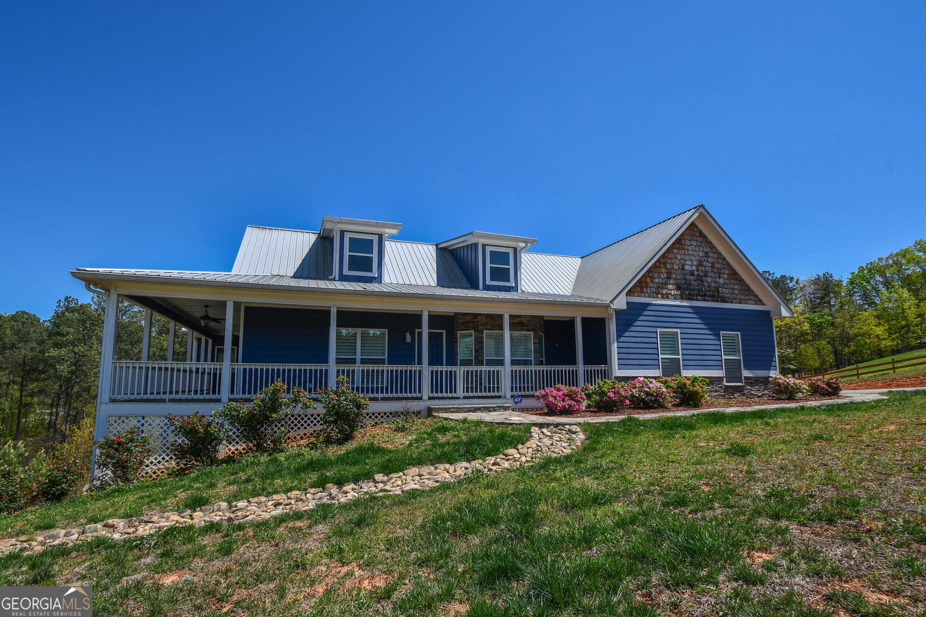 Welcome to this 3000 sq ft high-end country home with serene mountain views. A covered porch on two sides of the home offers panoramic mountain views. Also features metal roof (greater durability), a Generac Guardian 22kw residential generator, and plantation shutters throughout. Step inside to a dramatic open space with wood cathedral ceiling that soars over expansive kitchen, dining room, and living area. Kitchen has granite counters/island, walk-in pantry, gas range, and unbelievable storage. Living area, looking out on mountains, has corner gas fireplace with stone mantel to ceiling. Main level also includes master bedroom with walk-out private sunroom (mountain views again), large master bath with walk-in shower, granite counters, and double vanities. Also, half bath and laundry room. Downstairs are two secondary bedrooms (one with private screened porch), an office, full bath with double vanities, second family room, and large unfinished basement area with built-in shelving and work sink. Location gives you the twin benefits of being in the country and yet close to all that Dahlonega has to offer.
