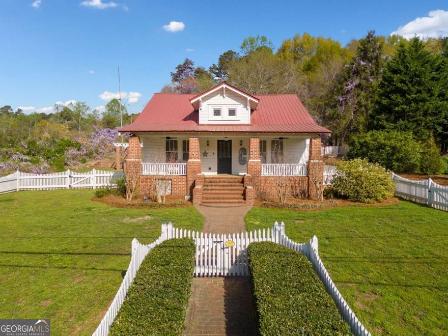 Welcome to a truly special slice of history in the heart of downtown Ball Ground! This beautifully restored Craftsman Bungalow is only steps away from Ball Ground Elementary. It offers a perfect mix of classic character and modern comfort.    Inside, you'll be enchanted by the heart pine floors and tall ceilings. The ornate moldings and five fireplaces bring a touch of old-world charm. Stained glass windows and original mantels share tales from the past. New electrical, plumbing, and HVAC systems, along with a beautifully updated kitchen with GE Cafe appliances make daily living easy.    The main-level primary bedroom is a true retreat.  The Primary suite closet has the washer & dryer in it for easy access and en suite bath with double vanities, a tiled shower, and plenty of built-in storage.  An additional bedroom on the main level with en suite bath is perfect for guests!     Upstairs, you'll find a spacious bedroom and flex space for work or play plus a shared bath - a versatile layout ideal for family, guests, or home office space. And with spray foam insulation in the attic, you'll enjoy energy efficiency year-round.    Set on over half an acre - one of the largest lots in downtown Ball Ground - this home offers room to grow, relax, and entertain. The 2-story barn with 6 stalls and a fenced area perfect for animals, original detached garage, brick patio, and fenced garden area invite outdoor living at its finest.    This is more than a home - it's a rare opportunity to own a piece of Ball Ground's past, fully restored for your future.
