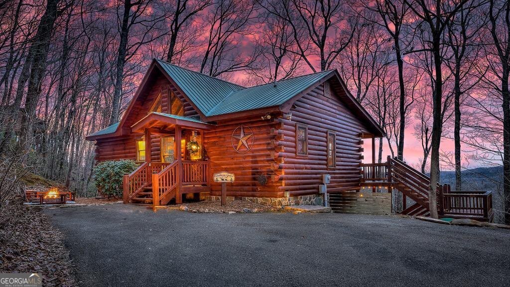 Come experience the charm and natural beauty of the North Georgia Mountains at "Southern Grace," a fully furnished, turn-key 2BR/2BTH true log cabin featuring breathtaking long-range and sunset views from two spacious covered decks-ideal for sipping morning coffee or unwinding with an evening glass of wine. This inviting home offers an open-concept layout with pine wood floors and walls, vaulted ceilings with exposed beams, a dramatic floor-to-ceiling stone gas fireplace, a generous dining area, and a wall of windows that flood the space with natural light. Both bedrooms are conveniently located on the main level, each with an ensuite bath and shower/tub combo-the primary suite includes a king bed and the guest bedroom a queen. Step outside to enjoy the firepit, perfect for roasting s'mores, and take advantage of the EV charger plug for your electric vehicle. Situated in a quiet community with paved roads, the cabin is just 15 minutes from Downtown Blue Ridge with access to shopping, dining, and outdoor fun like tubing or canoeing on the Toccoa River, hiking, horseback riding, fishing, gem mining, and boating on Lake Blue Ridge. Drive just 20 minutes in the other direction to reach historic Downtown Ellijay, Georgia's Apple Capital and Mountain Biking Hub, home to some of North Georgia's best wineries. Whether you're looking for a weekend getaway, full-time mountain retreat, or an investment property-this home generated $47,000 in gross rental income last year-"Southern Grace" delivers it all. Schedule your private tour today!