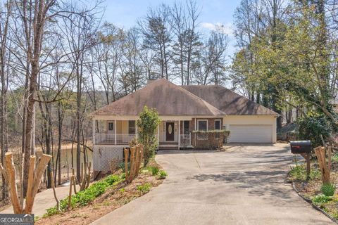 Single-family residence for sale at 3302 Hickory Point, Gainesville, GA, showcasing a charming exterior with a sloped roof, surrounded by trees and a driveway leading to the entrance, reflecting the appeal of lake living near Lake Lanier.