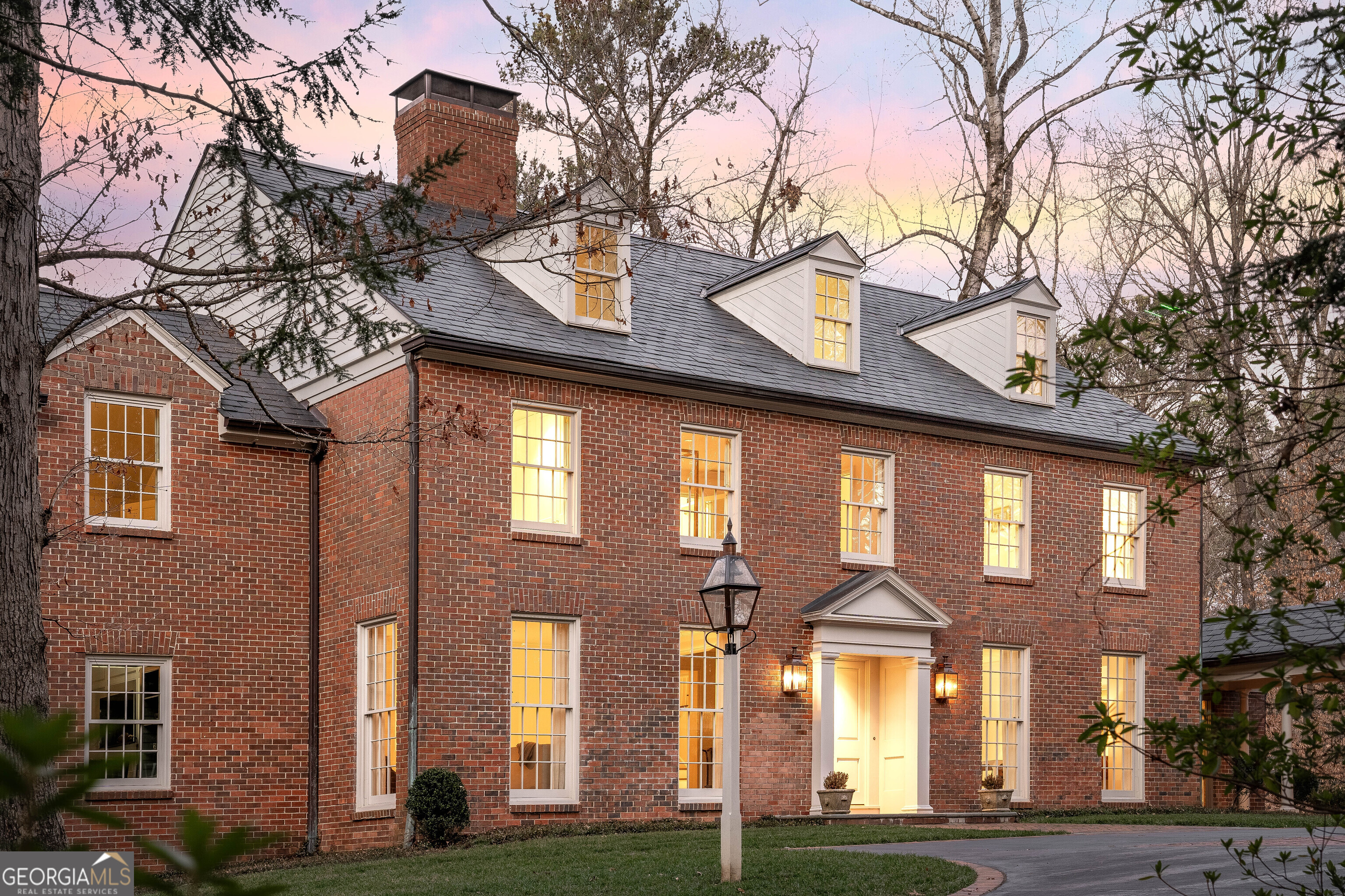 Nestled discreetly along Tuxedo Road, where Blackland and King Road converge near Chastain Park, discover a masterpiece of timeless elegance. Designed by renowned architect Stan Dixon in collaboration with interior designer Carolyn Malone, this heirloom-quality residence epitomizes discreet luxury. A stately gated entrance opens to reveal classic Georgian architecture adorned with a 200-year Birmingham slate roof and copper gutters, complemented by handcrafted furniture-grade windows and doors. Inside, the minimalist design of Belgian oak floors exudes modern sophistication, while the main level seamlessly blends daily living and entertainment. A spacious family room with a cozy fireplace overlooks a private tree-lined balcony, ideal for tranquil moments. For the discerning professional, a sophisticated gray-paneled office offers serene views of both front and back gardens. Indulge in indoor/outdoor living with effortless access to the kitchen and breakfast room, or descend to the fully finished basement-a haven boasting a guest suite, exercise room with full bathroom and steam shower, wet bar, game room, media room, and wine cellar. Upstairs, five bedrooms include a primary suite with barrel ceilings and a fireside bath, alongside four secondary bedrooms connected by Jack and Jill bathrooms. The fourth level presents versatile space for a classroom, media room, or art studio, complemented by a light-filled laundry room equipped with custom concrete folding tables and ample storage. Enhanced by a whole-house generator, tankless water heater, and top-tier HVAC with Aprilaire Healthy Air System, comfort is assured year-round. Cleverly integrated storage solutions abound, from hidden dining room cupboards to expansive closets throughout. Outside, a detached three-car garage with unfinished space above and a spacious motor court ensure ample parking for guests. This private estate is move-in ready, offering proximity to Buckhead's vibrant tech/business district, premier shopping and dining, and top-rated public and private schools. Enjoy membership privileges at the esteemed Cherokee Town and Country Club-an unparalleled lifestyle awaits at the intersection of Tuxedo Park and Chastain Park, Atlanta's most coveted neighborhoods.