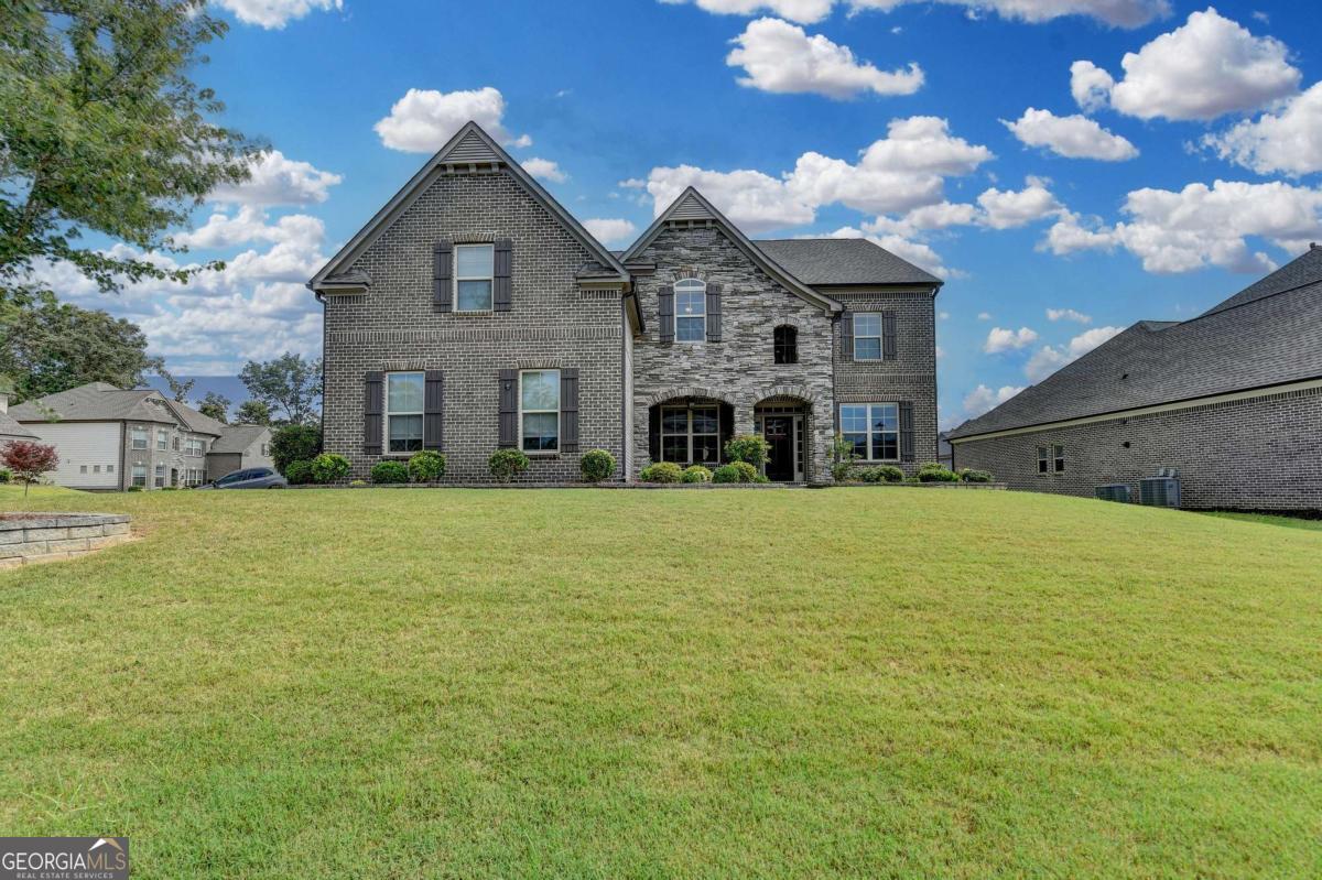 Welcome to this beautifully maintained home in Suwanee, featuring four sides of brick and stone construction. This is the only home in the neighborhood with the Wilmington floor plan by CalAtlantic Homes that includes a three-car garage. It's truly better than new and feels as if it was just built. This highly sought-after layout offers five spacious bedrooms and four full bathrooms, along with a separate study/living room, a formal dining room, and a large game room perfect for entertaining or relaxing. The open-concept kitchen is a chef's dream, equipped with 42-inch cabinets, abundant countertop space, quartz countertops, a white ceramic farmhouse sink, a 36-inch cooktop with vent hood, and a butler's pantry. It also features an enormous walk-in pantry, undercabinet lighting, and modern farmhouse pendant lights over the island for added style and functionality. The owner's suite includes a private sitting area and a luxurious bathroom with a freestanding soaking tub, an oversized walk-in shower, double vanities, and a dedicated makeup vanity. The custom walk-in closet is the size of a secondary bedroom and comes complete with a built-in organization system. All secondary bedrooms are generously sized and feature level five carpeting for added comfort. The backyard is large, level, and includes a covered patio, ideal for outdoor gatherings and relaxation. Located just five minutes from Suwanee Town Center, this home offers convenient access to Peachtree Industrial Boulevard, Satellite Boulevard, and Buford Highway. It's truly one of the best homes in one of Suwanee's most desirable communities.