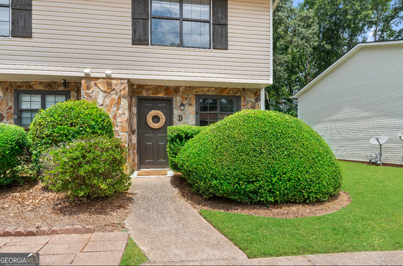 Welcome to this inviting end-unit townhome just off Lake Lanier offering a perfect blend of privacy, comfort, and convenience. As part of a quiet, well-kept community, you'll have access to two private docks ideal for swimming, fishing, or enjoying life by the water. Just behind the home, you can walk to Holly Park, a hidden gem that leads to a scenic riverbank, offering a peaceful escape anytime you want! Paul Park has a pavilion picnic tables. This well maintained townhome boasts stacked stone exterior accents and an attached driveway for flexible parking. Inside, you'll find a floor-to-ceiling stacked stone fireplace that serves as a stunning focal point in the heart of the home, which offers a blank canvas to design a space that fits your lifestyle from cozy and relaxed to modern and vibrant. The kitchen is equipped with updated stainless steel appliances, pantry, and a fresh clean feel ready for everyday living or entertaining guests. Upstairs, enjoy two spacious en-suites, including a primary suite at the back of the home complete with it's own private deck. Ideal for roommates, guests, or multi-generational living, each with plenty of privacy and natural light. Step outside to your covered back patio overlooking a backyard with peaceful wooded views, creating a perfect retreat for morning coffee or evening relaxation. Located just outside the hustle and bustle, this home offers the perfect balance of tranquility and convenience while close to grocery stores, shopping, dining, healthcare, reputable schools, and major highways for an easy commute. Don't miss the opportunity to enjoy low-maintenance living in a scenic and accessible location!
