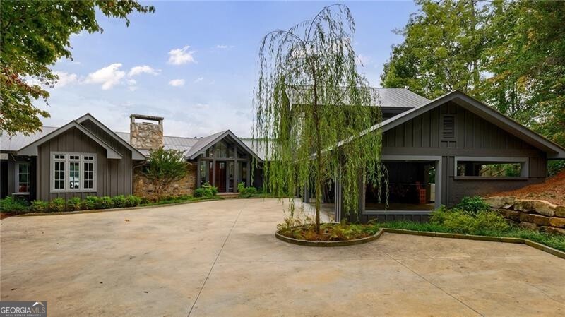 Lakefront JEWEL on Lake Rabun's GOLD COAST! Custom designed by architect Bob DiFiore, and expertly constructed by Steve Jones Construction, this extraordinary home hugs the shoreline overlooking a wide expanse of Lake Rabun's Little Basin. Awe-inspiring views will captivate you from all the living spaces, including the luxurious primary bedroom with spa-like bath and separate office, aa well as in the king-sized guest suite on the main level.  Vaulted ceilings, walls of glass along the lakeside, sky lights, hardwood floors are just a few of the luxury features . The open-floor plan of the main level connects gatherings from the kitchen to the dining and living rooms . In the living room a beautiful stone fireplace competes with the jaw dropping view of the lake from the glass wall of windows. Just steps away , enjoy the vaulted ceiling screened porch with its surrounding view of the lake during warm weather months or cozy up by the dramatic stone fireplace in cooler weather while you watch the flat screened TV. From the screened porch, step out on to the Grilling Deck for the chef's convenience . The exterior door to the deck may be used to reach the firepit on the point for marshmallow roast or conversations.  The most gourmet chef will find the high-end kitchen appliances perfectly situated for successful entertaining.  The well-designed, walk-in pantry organizes all small appliances while keeping them out of site.  The half bath and neighboring laundry room complete the main level of this well designed home. Upstairs are two spacious guest suites with private baths. The lower level boasts a double bunk room & Den / TV room that has a 5th full bath. There is Easy access from this level to the newly constructed, two slip boathouse that accommodates a pontoon and ski boat. Power outages are not a problem for the Generac generator located behind the two bay carport and one bay garage. The proximity to Halls Marina, The Lake Rabun Association Pavilion for community events, restaurants and hotel are unbeatable.  The town of Clayton with its charming shops, outstanding restaurants and modern hospital facilities is just a 20 minute drive.  Expand your outdoor adventures with Golf, fishing, tennis, hiking, white water rafting close by. This is an opportunity to own an irreplaceable property on Lake Rabun, Georgia's Lake Como!