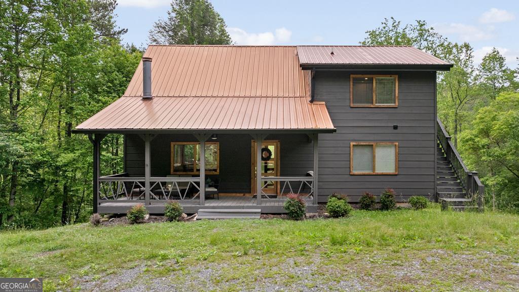 SOLD TURNKEY - Fully Furnished & Airbnb Ready! Discover 149 Happy Hollow, a newly remodeled 3-bedroom, 3-bath luxury-rustic cabin with loft and full game room/movie room, boasting no HOA or restrictions and an impressive 151 feet of serene Wolf Creek frontage. Perched above the tranquil waters, this exquisite property blends modern upgrades with timeless cabin charm, offering a flexible layout perfect for Airbnb hosting, full-time living, or an indulgent second home retreat. Lovingly maintained and thoughtfully enhanced, it has served as both a cherished personal escape and a successful part-time rental. The upper level showcases a spacious game loft, a private balcony bedroom, and a full bath, while the main level features a chef's kitchen adorned with a marble island, custom wood cabinetry, stainless steel appliances, pantry, and open dining space. The inviting living room exudes warmth with hardwood floors, a crisp white gas-log fireplace, and soaring ceilings. A main-floor bedroom offers a grand walk-in closet and a spa-inspired ensuite bath. The finished basement presents another bedroom and bath, an expansive game/movie room, laundry area, and direct walkout to a charming creekside sitting area. Outdoors, a sprawling back deck, brand-new hot tub, and magical firepit with string lights invite year-round enjoyment. Recent upgrades include all new flooring, paint, kitchen and bath renovations, lighting, fireplace, well, water filtration system, landscaping, and a gently winding gravel path leading to the creek. Perfectly positioned just minutes from both Blue Ridge and McCaysville, this easy-access cabin offers unmatched convenience without sacrificing privacy. Whether you envision it as a permanent residence, a weekend hideaway, or an income-generating investment, 149 Happy Hollow delivers on every level! Located next to many outdoors things to do such as Fall branch Falls, Swinging bridge on the Toccoa River, Jacks River Falls and Bald River Falls, Sea Creek Falls, Aska adventure area and more! Yet only a quick drive from Downtown Blue Ridge and Downtown Mccaysville!