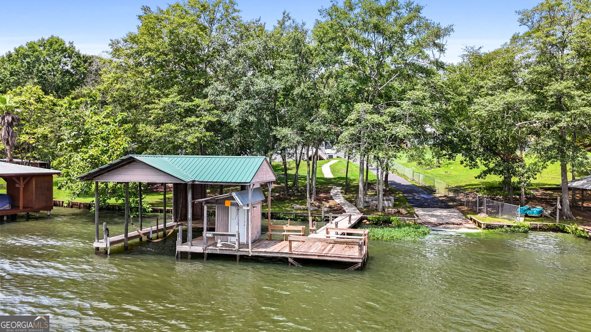 "THE CHANCE SELLS TEAM" presents a fabulous deal where you can have 2 homes on the lake for the price of one! This is a "DEEDED" Waterfront lot, sitting on a 1.41 acre lot, with a dock and single covered boat lift too. 5-6 feet of water depth at the front of the dock and this is only one out of 3-4 other properties around this area, that has a Boat Ramp Launch pad in your own backyard. Otherwise, you would have to put your boat(s) or jet ski's in at the marina. The main home is a triple wide boasting a large kitchen with island and is open to the great room, den, eat-n-area with some views to the lake. Split bedroom plan with a spacious primary bedroom and bathroom. Secondary bedrooms are large sized with nice sized walk-in-closets too. Big laundry room with a built-in-desk area. Big covered back porch and an outbuilding. 2nd home is an older home that will need some TLC. Added to it is a huge great room area that is sitting on a concrete slab. (HOME IS BEING SOLD AS-IS), as this is an Estate. Seller does not have a seller disclosure for this property, but said they may know of some things about it, so if anyone has any questions, they would be glad to answer and help if they can! Great deal on this place! I love the big open view to the water this shoreline has. You can see the water for over a mile when you look to your left and 3/4 mile when you look to your right while standing on the dock! Give us a call for your easy showing of this place today! Thanks, Chance.