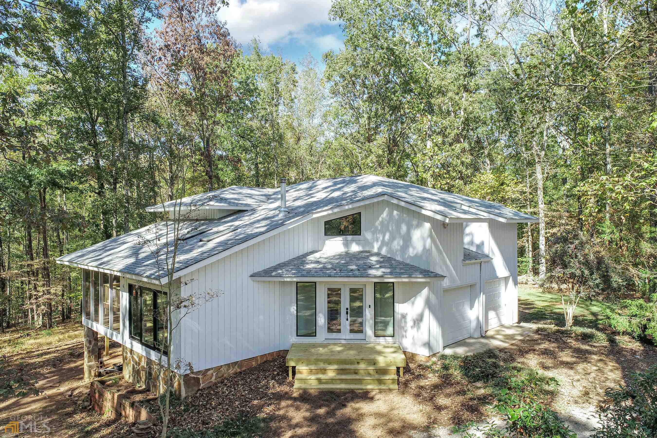 Forest views, screened porch and a deck for relaxing and entertaining! Proudly displaying the charisma of a contemporary home, this 3-bedroom, 2.5-bathroom is perfectly situated on 22 acres in Arnoldsville. Step into an interior embrace that includes an open layout, natural light, stylish fixtures, neutral color palette, and luxury vinyl flooring throughout. The living room features a vaulted ceiling, large windows and a wood burning stove. Stylish kitchen charms with fresh updates including quartz counters, stainless appliances, and a beverage cooler. The master bedroom includes a walk-in closet and private bath with a double vanity and step-in shower. The other two bedrooms are also situated above the ground floor for privacy. A circular driveway (no backing out!) makes for a grand welcome and is connected to an attached two-car garage. This property features fenced pasture, a 36x36 barn with two stalls, trails amongst the hardwoods and a creek. Painless commute to the University of Georgia and downtown Athens means more time to enjoy this beautiful property. This one checks your "must have" boxes.