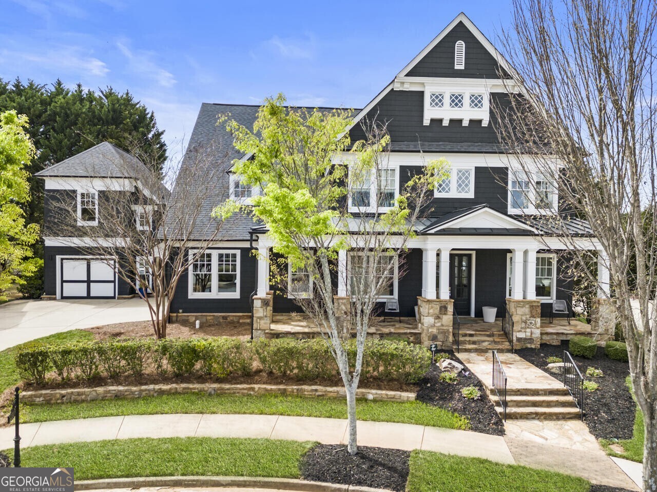 Nestled within Milton's sought after Heritage at Crabapple community in the heart of and walking distance to Crabapple market village, this exceptional home epitomizes luxury and sophistication while offering convenience and style that makes you feel right at home. Constructed in 2015 by builder Ashton Woods, this residence showcases the modern Callaway model with extensive upgrades, impeccable craftsmanship, and upscale fixtures and finishes throughout. Step inside from the inviting covered front porch to a spacious and desirable floorplan accentuated by a grand two-story foyer, expansive ceilings, upgraded light fixtures, over 100 recessed mini-can lights with dimmer switches, and detailed trimwork that add to the overall contemporary style and beauty of the home. The gourmet chef's kitchen is truly the heart of the home and is centered around an oversized eat-in island with cushion glide drawers. Floating shelves adorn the subway tile wall and a drop-ceiling block offers a modern aesthetic with indirect multi-color Hue lighting. The kitchen has been upgraded with extensive floor-to-ceiling cabinetry and top-of-the-line Jenn-Air appliances, including a pro gas range and vent hood, dual ovens, French Door 42" built-in refrigerator, and under-counter Viking Ice Nugget machine, microwave and warming drawer. Features such as the hidden walk-in pantry, butler's pantry with wine storage, and mudroom, complete with floor-to-ceiling cabinetry, built-in bench seating and an integrated desk, creatively blend form and function. The open floor plan is equally suited for everyday living and hosting friends and family. The living room is beautifully appointed with an integrated Heat & Glo fireplace encased in a modern silestone surround, and framed by a bench and large built-ins cabinets with drawers for added storage. This home also represents the epitome of indoor-outdoor living: NanaWall folding glass doors ensure a seamless transition to a spacious covered patio that invites year-round alfresco dining and leisure. Both the living room and patio have been upgraded with a Klipsch 5.1 in-ceiling surround sound system with Bose outside speakers that encourage entertaining. The freshly landscaped, private backyard invites a custom outdoor oasis with the perfect pool-ready lot. In addition to the first floor bedroom and full bathroom, a den space at the front of the home offers versatility as a private office, library, or keeping room. Wood floors, modern cove crown molding, wainscoting, and three recessed art niches in the hallways and dining room grace the first floor. Retreat to the elegant primary suite upstairs, featuring a spacious ensuite with dual vanities, an oversized 12-foot rectangular shower with dual tile benches and rain showerhead, and luxurious Kohler free-standing tub against a mosaic tile surround. For added convenience, the walk-in closet offers direct access to the laundry room, which features a silestone folding counter, extensive cabinetry and a drop-in sink. Bedrooms throughout the home offer comfort and style with custom California Closets and elegant window treatments from the Shade Store. Enjoy the convenience of an attached 2-car side entry garage with cabinetry and overhead storage. The detached 3rd car garage has a finished loft apartment complete with a full bathroom that is perfect for a private guest retreat, quiet office space, or hangout and gaming area. The convenience of this prime location is unmatched with walkable access to restaurants, coffee shops, retail, markets, and fitness studios. Enjoy the proximity to award-winning schools, local library, and green space for concerts, events and entertainment in Crabapple. With private community amenities including a clubhouse, pool, tennis courts, play ground, park and easy access to downtown Alpharetta, the Avalon development, and Historic Roswell, this turn-key home presents an unparalleled opportunity for upscale living in a vibrant community.