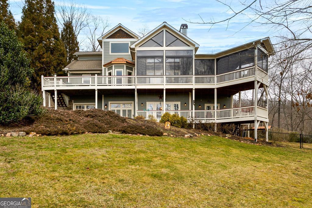 Welcome to your dream home with breathtaking views of the Lake, Mountain, and Brasstown Bald, nestled in the picturesque town of Hiawassee. This custom-built masterpiece features 3 bedrooms, 2.5 bathrooms, and an oversized 2-car garage, all conveniently close to town and surrounded by exquisite landscaping with seasonal lake glimpses. The main level invites you in with a seamless flow from the welcoming foyer to the grand great room, featuring a dramatic floor-to-cathedral ceiling stacked stone gas log fireplace. Relish the harmonious blend of drywall and wood as you enjoy meals in either the breakfast nook or the well-equipped kitchen, adjacent to the formal dining room. The spacious Master Suite stands out with its direct access to a screened/vinyl enclosed porch. Enjoy the spacious master bath boasting a luxurious tile shower and garden tub. Additional amenities include a deck, an expansive laundry room, a half bath, and a sophisticated pantry equipped with a dumbwaiter connecting to the garage. Explore the loft and you'll find an inspiring study area with a built-in desk for two, offering stunning views and substantial storage thanks to a large closet. The terrace level, accessible via a private entrance, hosts two bedrooms, a bathroom, a kitchenette, and a cozy family room with a stacked stone gas log fireplace, plus a porch for relaxation. This property offers abundant parking options with two driveways and includes a concrete pad designed for a 40' RV, complete with a 50 amp hookup. Delight in the granite finishes throughout the home and numerous upgraded features such as a security system, a sound system, and a whole-home Generac generator. This exceptional property deserves a place at the top of your must-see list!