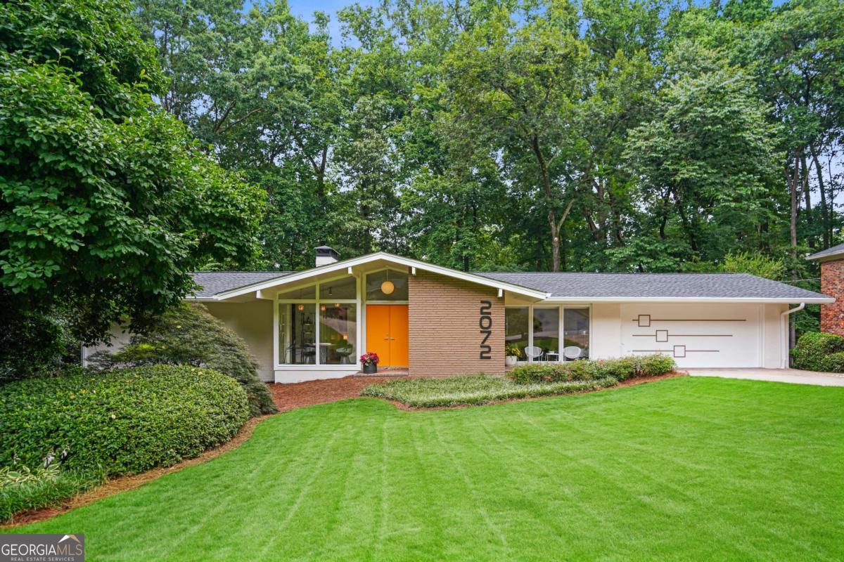 Yes, dreams do come true! You've been searching for a true mid-century modern home with vaulted ceilings, walls of glass, private outdoor terraces, and plenty of space for entertaining or relaxing at home. This 1963 beauty has been lovingly updated with modern conveniences while maintaining aspects of its mcm charm. Blonde hardwood floors throughout the main level contrast beautifully with the original slate floors in the foyer. New sliding doors complement original glass gallery walls allowing maximum natural light and views of the private wooded lot. A dramatic living room offers exposed brick wall, fireplace, floor-to-ceiling wall of windows and a beamed ceiling running through to the outdoor terrace. The main level of this pristine home offers 3 bedrooms, 2.5 bathrooms, and a newly renovated owner's suite featuring a double vanity and large double step-less shower. A finished terrace level includes a huge media/family room with 2nd fireplace, 4th bedroom, full bathroom, additional kitchen and dining area, and unfinished storage room for all your keepsakes. An air-conditioned sunroom is perfect for a home office or fitness studio as it overlooks the wooded beauty of the backyard. Updated mechanicals, roof, and fresh exterior paint make this home truly move-in ready! The highly sought-after Amberwood neighborhood offers easy interstate access and is close to shopping, schools, CHOA, Emory/CDC and other amenities.