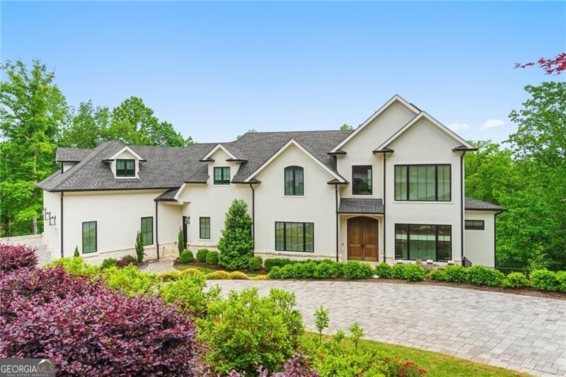 Don't miss this rare opportunity to own an exquisite estate in the prestigious, gated community of Country Club of the South. One of the newer custom-built homes in the neighborhood, this modern masterpiece showcases exceptional craftsmanship and refined elegance throughout. Beyond the impressive double oversized Mahogany doors, a soaring foyer sets the tone for the home's grandeur, flanked by a striking open staircase and an elegant dining room adorned with custom built-ins and designer lighting. The heart of the home is the light-filled chef's kitchen, a true showstopper featuring top-of-the-line Wolf and Sub-Zero appliances, sleek quartz countertops, and a dramatic center island that comfortably seats ten-perfect for entertaining. Custom white oak cabinetry with a light gray stain extends to the ceiling, complemented by bold accent tones that add a sophisticated designer touch. The soaring great room is a stunning focal point, featuring a sleek modern fireplace, solid beam accent shelving, and seamless flow-perfect for both sophisticated entertaining and quiet evenings by the fire. Upstairs, the luxurious primary suite offers dual custom closets and a spa-inspired bath with a soaking tub, exquisite marble tilework, and designer accents. A private bedroom suite over the garage-with its own entrance-is ideal for guests, teens, or an in-law retreat. An ideally positioned elevator whisks you to all three levels, including the spectacular terrace level with soaring 14-foot ceilings. This level features a spacious family/media room, a dining area, and a stylish mini bar, along with two additional ensuite bedrooms and a large exercise room with its own bath. Outdoors, enjoy a panoramic golf course view from the expansive main-level deck or relax by the custom Pebble Tec pool and covered porch on the terrace level-both perfect for entertaining. This thoughtfully engineered home also includes 12.8 kWh of battery storage powered by 20 kW of solar panels, enabling essential off-grid functionality, along with a tankless water heater and comprehensive security system. Built with top-of-the-line materials and meticulous craftsmanship, this extraordinary home offers both style and substance in one of Johns Creek's most exclusive golf course communities. A must See!