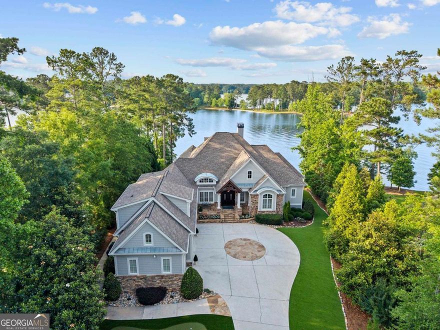 NEWLY RENOVATED LUXURY LAKEFRONT ESTATE WITH PANORAMIC BIG WATER VIEWS, JUST MINUTES FROM THE RITZ AND LAKE CLUB OFFERING RESORT STYLE LIVING AND IMPECCABLE CRAFTSMANSHIP. Perfectly positioned on a stunning lakefront lot in Reynolds Lake Oconee, this newly renovated family oasis offers elevated lake living just minutes from the Ritz Carlton and Lake Club. Designed by premiere builder Rick Buechler, this five-bedroom, eight-bath home centers around spectacular water views and resort-style amenities. The home greets you with a refreshed exterior featuring new trim, siding, and paint. A golf lover's dream, the front yard includes a private turfed putting green, ideal for practicing your short game just steps from the front door. Inside, the light filled main level opens with a formal dining room highlighted by a barrel ceiling, leading into a spacious great room with soaring ceilings, stone fireplace, and expansive lake views. The adjoining kitchen is equipped with Wolf double ovens and griddle range, warming drawers, two SubZero refrigerator/freezer sets, dual dishwashers, a wine fridge, and a stainless steel farmhouse sink. Custom cabinetry, a large center island, beverage bar, and butler's pantry add function and style. Flowing seamlessly from the kitchen, the all season keeping room has heated floors and stunning lake views. The newly remodeled primary suite offers a private sanctuary with motorized shades and built in closets. The en suite bath has been completely renovated featuring new tile, dual vanities, soaking tub, and a spa like shower. Adjacent, the office offers a peaceful space for remote work. Above the four car garage with golf lockers, a private apartment includes a full kitchen, living room, bedroom, bath, and dedicated workspace ideal for guests. Take the elevator to the terrace level with new engineered hardwoods, a great room with four screens, projector, and second full kitchen. Three guest suites have private baths with heated floors; two access the pool and balcony. A second laundry, gym, and lake access bath complete this level. Outside, enjoy a resort style infinity pool, sun ledge, firepit, and multiple seating areas with unobstructed lake views. Low maintenance turf surrounds the space. Two boat lifts and three Sea Doo lifts ensure easy lake access. Pre inspection complete and all items addressed. Truly move in ready. Membership available.