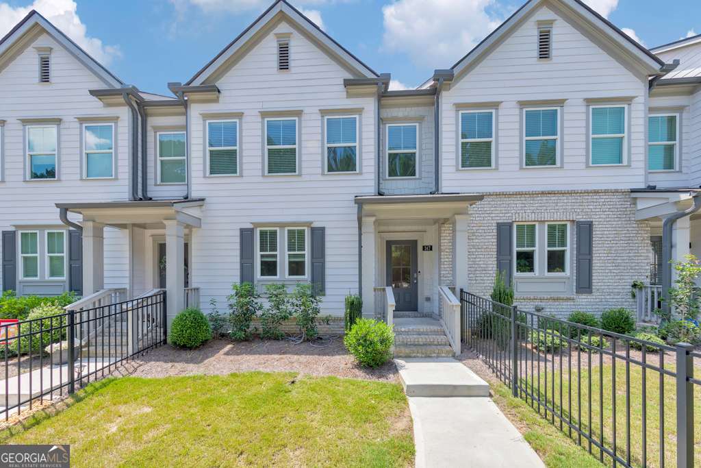 Welcome to this stylish 3 bedroom, 3.5 bathroom townhome in the sought-after Towne Lake Hills community in Woodstock! Investor-friendly with no rental restrictions! Built in 2022, this modern home features crown molding, recessed lighting, and an open-concept main floor perfect for entertaining. The chef's kitchen is equipped with white cabinetry, stone countertops, stainless steel appliances, a pantry, and a center island with seating. Enjoy cozy evenings in the fireside family room or step out onto the rear deck for fresh air. Upstairs, the spacious primary suite includes a walk-in closet and a spa-like ensuite with double vanities and a sleek glass shower. Two secondary bedrooms share a full bath, and a convenient laundry closet is located on the upper level. The terrace level adds flexible space with a full bathroom, bonus room, and access to the attached 2-car garage. A fenced front yard and unbeatable location just minutes from Downtown Woodstock and Noonday Creek Trail make this home a true gem.