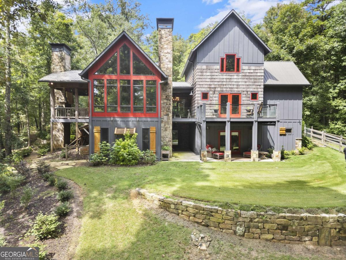 Escape to the heart of North Georgia wine country in this stunning 4 bedroom, 4.5 bathroom creekside luxury chalet, perfectly nestled in the mountains and less than five minutes from local wineries, apple orchards, and charming small-town attractions. Designed for both comfort and sophistication, this home combines rustic elegance with high-end finishes throughout. The main level welcomes you with soaring ceilings, walls of glass, and abundant natural light that frames beautiful views of Turkey Creek flowing just outside. Multiple stone fireplaces add warmth and ambiance, while an open floor plan seamlessly connects the great room, dining area, and chef's kitchen-ideal for entertaining or cozy evenings at home. This retreat offers space for everyone, with four spacious bedrooms each featuring a dedicated bath. The expansive primary suite is a private sanctuary, complete with a spa-like bathroom featuring an oversized tile shower, soaking tub, double vanities, and a walk-in closet. A bonus room offers flexible use as a home office, library, or playroom. For those who love to entertain, the lower level boasts a movie theatre and generous living space perfect for gatherings. Step outside to enjoy beautifully landscaped grounds, a creekside firepit, and multiple decks where you can relax and take in the fresh mountain air. Complete with a barn/workshop, a fenced area for your furry friends, and complete privacy, this would be a perfect full-time residence, private getaway, or income-producing investment. This North Georgia treasure is ready to welcome you home!