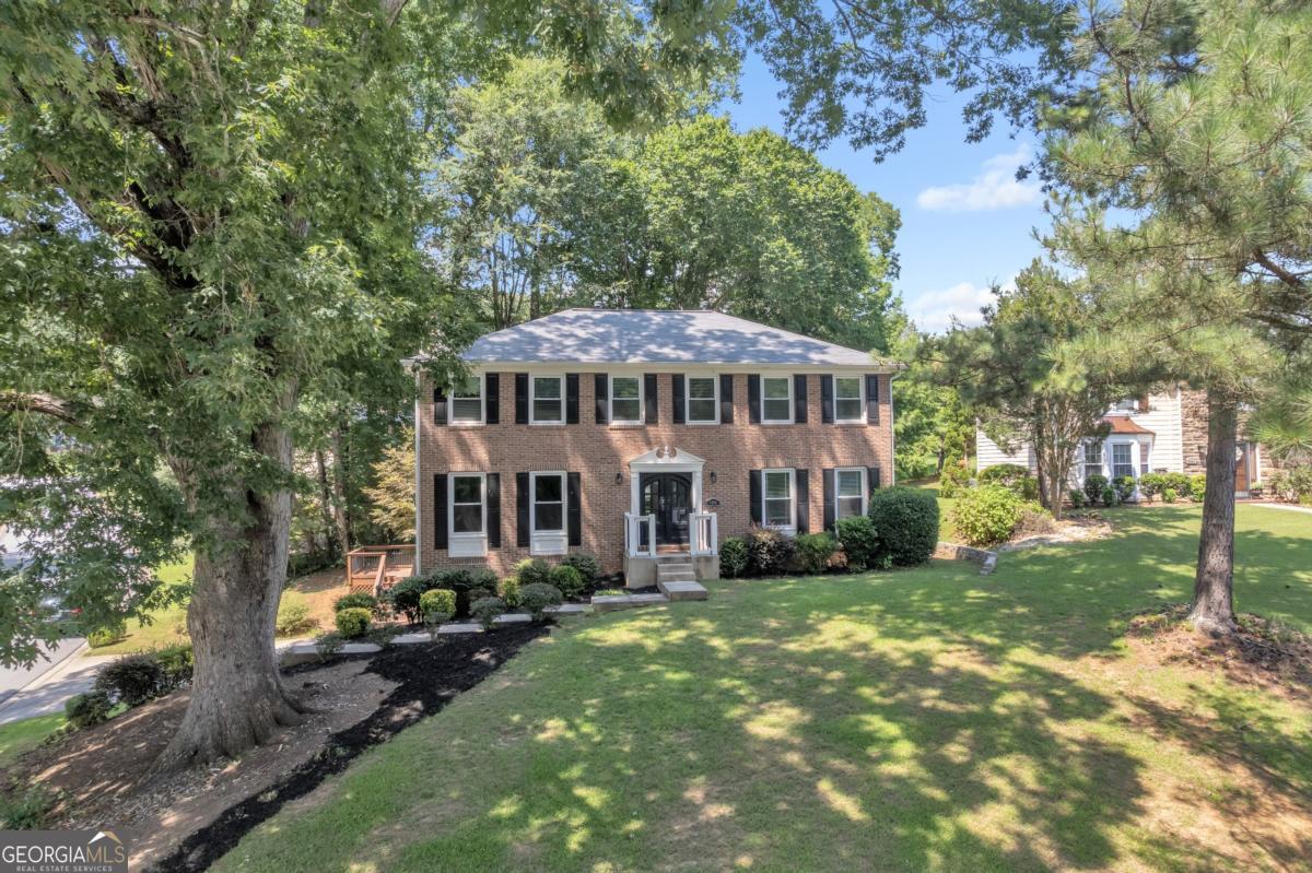 Welcome to 6960 Whispering Oaks Court, a beautifully customized traditional home in the heart of Stone Mountain. Perfectly positioned on a spacious corner lot just a short stroll from the lake, this 5-bedroom, 3.5-bath residence offers the perfect blend of timeless charm and modern functionality, ideal for growing families, multi-generational living, or buyers looking for space and serenity. From the moment you arrive, the striking front door and inviting curb appeal set the tone for what's inside. Step into the main level, where hardwood floors flow throughout a thoughtfully designed layout. Built-in shelving and cabinetry add a touch of elegance while offering smart storage solutions for everyday living. The open-concept kitchen is equipped with stainless steel appliances, stone countertops, and rich stained cabinetry, an inspiring space for both weeknight meals and weekend gatherings. The adjoining family room features a cozy electric fireplace and French doors that open to a multi-level deck, perfect for hosting guests or enjoying peaceful mornings with coffee. Upstairs, retreat to the oversized primary suite, complete with a generous walk-in closet and a spacious en-suite bath, your personal haven at the end of the day. Additional bedrooms are well-sized and filled with natural light, offering plenty of flexibility for home offices, guest rooms, or play spaces. Downstairs, the finished basement presents a fantastic bonus space for entertaining, lounging, or working from home, while still offering ample storage. Buyers will appreciate the pride of ownership throughout the home, including the durable hardwood flooring, well-maintained finishes, and abundant natural light. With proximity to the lake, convenience to local amenities, such as Stone Mountain Park and a quiet, friendly neighborhood setting, this home offers an exceptional opportunity to enjoy both comfort and value. Don't miss your chance to call 6960 Whispering Oaks Court home, schedule your private showing today!