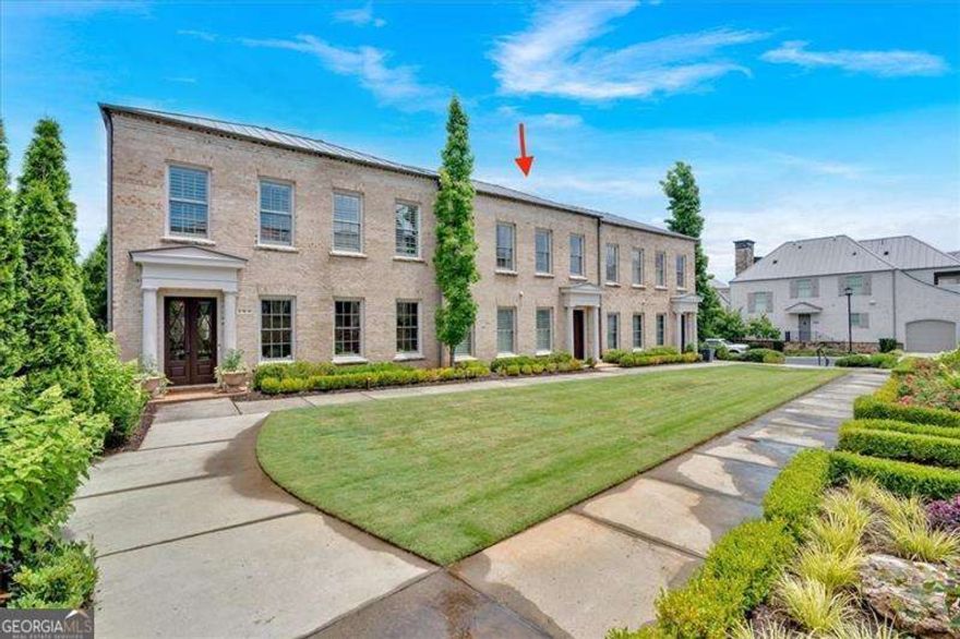 Discover the most sought-after rare townhome in Avalon/Alpharetta, featuring a two-story, extra-wide floor plan with a private carriage house and courtyard. This exquisite residence, as wide as a three-car garage, offers a spacious feel upon entry. Ideally located within walking distance to vibrant shopping, dining, and entertainment options, it provides unparalleled convenience in this dynamic live-work community. Enjoy easy access to GA-400, Downtown Alpharetta, the Farmers Market, Alpha Loop, and local events. This stunning home boasts 4 spacious bedrooms and 5 luxurious bathrooms. The open-concept main floor features a chef's kitchen with top-of-the-line appliances, including a Wolf microwave and coffee station, Sub-Zero refrigerator/freezer and wine fridge, and Monogram gas range and dishwasher. The kitchen seamlessly flows into the living and dining areas, enhanced by spectacular Nana accordion doors that open to a recently renovated courtyard with approximately 900 sq. ft. of rare, private outdoor space. Here, you'll find an outdoor Napoleon built-in grill, gas fireplace, accent lighting, automatic irrigation, a water feature, and advanced drainage-perfect for entertaining or serene relaxation. A flexible space on the main level can be customized as a bedroom, office, living room, or formal dining area, with convenient access to a full bath. Architectural elegance is evident throughout with gracefully curved corner walls and custom cove ceilings on the main level and in the master suite. Upstairs, three generously sized bedrooms, each with its own bath, offer comfort and privacy. The owner's suite is a true retreat, featuring an expansive walk-in closet meticulously designed for personalized organization and storage, paired with a spa-inspired bathroom. An app-controlled, ceiling-mounted speaker system is integrated into both the living room and outdoor living areas, completing this sophisticated home designed for modern living. The carriage house/studio private suite can accommodate a king-sized bed, dining and living room furniture, has a full bath, and a kitchenette. Located above the three-car garage, this private suite offers approximately 800 sq. ft. of versatile living space, perfect for a guest, in-law, or teenage suite. The versatile carriage house includes a fully equipped kitchenette with premium appliances, such as a full-size Sub-Zero refrigerator/freezer, Wolf microwave, and Profile dishwasher. Avalon has established high-speed fiber infrastructure to facilitate increased internet speeds for future needs. Additionally, GDOT has approved a loan to add new express lanes in both directions along a 16-mile stretch of Georgia 400 to improve traffic flow.