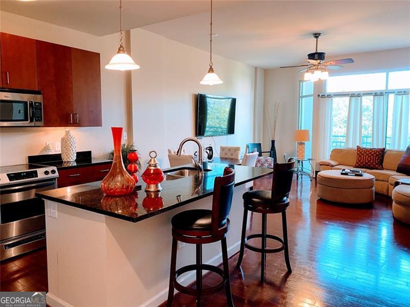 Spectacular Cosmopolitan! This spacious open concept 1 bedroom, 1.5 bathroom condo with a walkout balcony is conveniently located within walking distance of shops, dining, The living room/dining room/kitchen/powder room feature high ceilings and hardwood floors. The kitchen is equipped with granite counters and stainless steel appliances, and pantry. The primary bedroom has new LVP flooring. The private primary bathroom features a walk-in shower w/separate tub, double vanity and the large walk in closet with stackable washer & dryer. An assigned parking spot in gated garage. Close to Path400 trail, Marta, and I75/85. Unit is UNFURNISHED. Building Amenities include swimming pool, theater and billiards room, gym, 24 hr concierge, and controlled accessed building entry. Owner pays for water. Tenant is responsible for electric and internet/cable. NO pets of owner or visitor allowed. No smoking inside the unit. Minimum Lease term is 12 months.