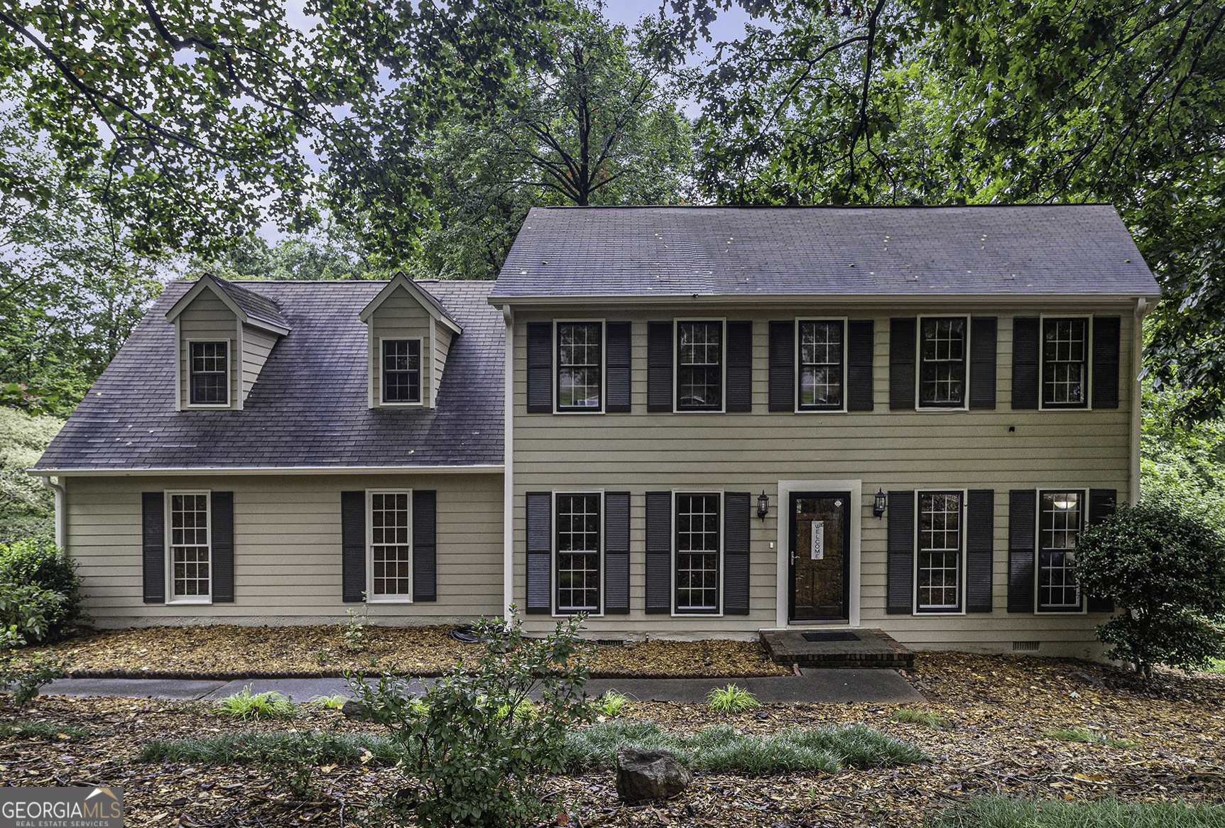 975 Branford Lane NW - a 4-bedroom, 2.5-bath John Wieland Colonial nestled in the established Huntington neighborhood of Lilburn. Situated on a generous 0.72-acre lot, this two-story home offers over 2,500 square feet of comfortable living space with timeless curb appeal and mature landscaping. Step inside to find a spacious and inviting layout perfect for everyday living and entertaining. The main level features a welcoming foyer, a formal living room and dining room, a cozy family room, and a stunning sunroom filled with natural light and serene views of the backyard - perfect for your morning coffee, a home office, or an afternoon retreat. The kitchen offers plenty of cabinet space and flows effortlessly into the breakfast area. Upstairs, you'll find four well-sized bedrooms including a private primary suite with an en-suite bath. With ample closet space throughout, this home provides room for anyone to live and grow as time goes on. Best of all, this home is within walking distance to the Huntington Recreation Club, where members enjoy access to a full Olympic-sized swimming pool - a true hidden gem for outdoor lovers and active families. Located in the Berkmar school cluster with easy access to parks, shopping, and dining, this home is a wonderful find in Gwinnett County. No HOA dues - just classic charm, great community amenities if looking to take advantage, and a spacious serene backyard with wooded views.