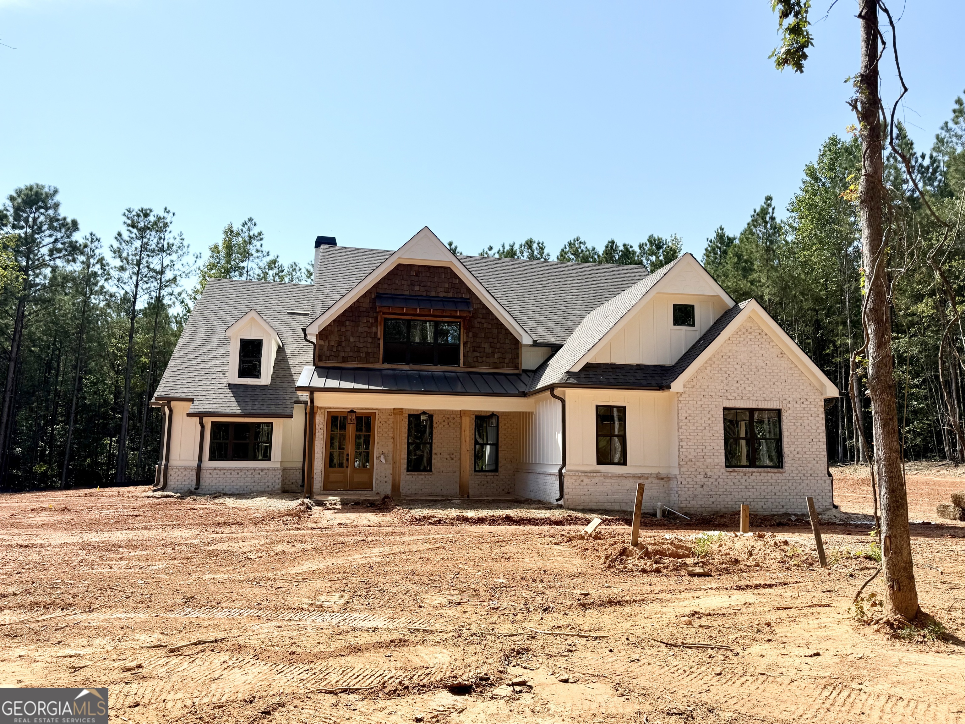 Exceptional Farmhouse Retreat on 3.6 Acres in Prime Sharpsburg Location Welcome to Pinegate! - where timeless design, modern comfort, and convenience come together. Nestled on a serene 3.6-acre lot just minutes from Peachtree City, Senoia, and Newnan, this stunning custom home offers the perfect blend of peaceful privacy and accessibility. Step inside and experience an open, inviting floor plan designed for both everyday living and effortless entertaining. The heart of the home is the chef's kitchen, complete with a striking center island with bar seating, stainless steel appliances, an oversized walk-in pantry, and solid surface countertops - all seamlessly open to the expansive great room featuring a cozy fireplace and custom built-in. Retreat to the vaulted, main-level owner's suite, a tranquil escape with a spa-like ensuite bath including a freestanding soaking tub and a generous walk-in closet. A secondary bedroom and full bath on the main floor offer ideal flexibility for guests or home office needs. Upstairs, you'll find two additional bedrooms, two full baths, a spacious bonus room perfect for a playroom, media space, or gym, plus a loft. Every detail in this home has been thoughtfully considered: 10' ceilings on the main level, rich hardwood floors, stunning custom trim, spray foam insulation, and full irrigation surrounding all four sides of the home. The vaulted, covered rear porch with outdoor fireplace and cedar accents invites you to relax and unwind while enjoying your peaceful acreage. With a 3-car garage, mudroom, and custom cabinetry throughout, this home is as functional as it is beautiful. Don't miss your chance to own this exceptional home.