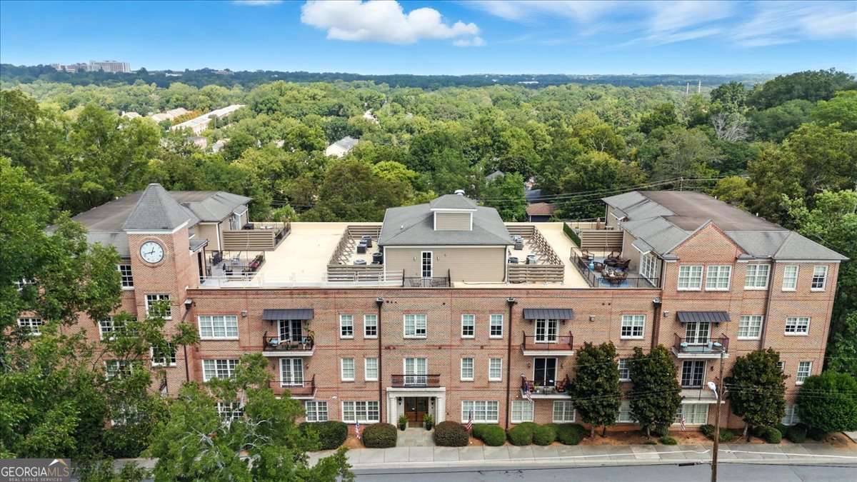 This elegant four-sided brick building makes a striking first impression with its classic design and enduring character. Within the residence, the sophistication continues as you are immediately greeted by the timeless elegance of grand columns that define the dining room as its own sophisticated space. Gleaming hardwood floors, soaring 10-foot ceilings, and an abundance of natural light set the tone for an open and airy floorplan. The great room is both stylish and inviting, enhanced by recessed lighting, custom built-in bookshelves, and a cozy fireplace perfect for relaxing on winter nights. Through French doors, the private patio offers a quiet retreat for morning coffee or evening unwinding. The gourmet kitchen is a chef's dream, boasting Bosch stainless steel appliances, granite countertops, and endless cabinetry. Thoughtfully designed to overlook the great room, it is ideal for both entertaining and everyday living. This is not your typical condo, featuring three bedrooms and three bathrooms, including two primary suites, the home offers remarkable flexibility. Whether you need space for a teen suite, an in-law retreat, or a private office on the opposite side of your bedroom, the possibilities are endless. Both primary bathrooms feature double vanities, while the main suite elevates the experience with a stand-up shower, soaking tub, and dual closets designed for those who love to shop or simply love their own space. Adding to the charm, a Juliet balcony allows you to open the doors to crisp fall air and the sounds of the season. Peace of mind comes easily here, as the HOA covers nearly everything. Exterior maintenance, gas, water, insurance, termite protection, pest control, and trash are all included, allowing you to simply turn on the power and relax. The condo also provides ample visitor parking, a deeded parking spot, and a private storage unit with electrical. For seamless convenience, the elevator carries you directly from the parking garage to your condo and up to the rooftop observatory, where panoramic views provide both tranquility and the perfect backdrop for entertaining. This residence is located just steps from the vibrant Marietta Square, where you can enjoy year-round festivals, concerts, restaurants, art shows, fireworks, and seasonal celebrations for all to enjoy. Outdoor enthusiasts will also appreciate being just minutes from Kennesaw Mountain, offering endless opportunities to hike, bike, or enjoy a leisurely stroll surrounded by nature. With quick access to I-75, only 15 minutes from Truist Park and The Battery, and a boutique community of just 18 units, this home offers the perfect balance of charm, convenience, and exclusivity. Opportunities like this are rare, and finding a home of this caliber, in this location, at this price, is truly extraordinary. All that's missing is you!