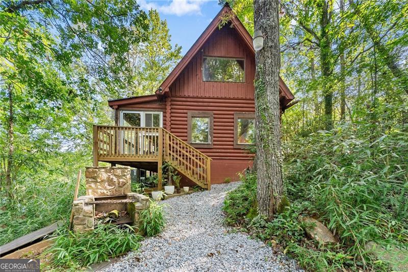 This beautiful lake house cabin sits on the Etowah River Watershed Lake, offering the ultimate in peace and seclusion. Featuring an open floor plan with gleaming hardwood floors and updated kitchen, this spacious home is perfect for vacation getaways or full-time living. Wake up to serene lake views from the oversized master suite, complete with its own private deck ideal for your morning coffee or quiet evenings under the stars. Step outside to enjoy the private dock and an entertainers dream deck with plenty of built-in seating, perfect for gatherings, fishing, or simply soaking in the natural beauty. Don't miss this rare opportunity to own a 5 acre piece of lakeside paradise in one of North Georgia's most charming towns.