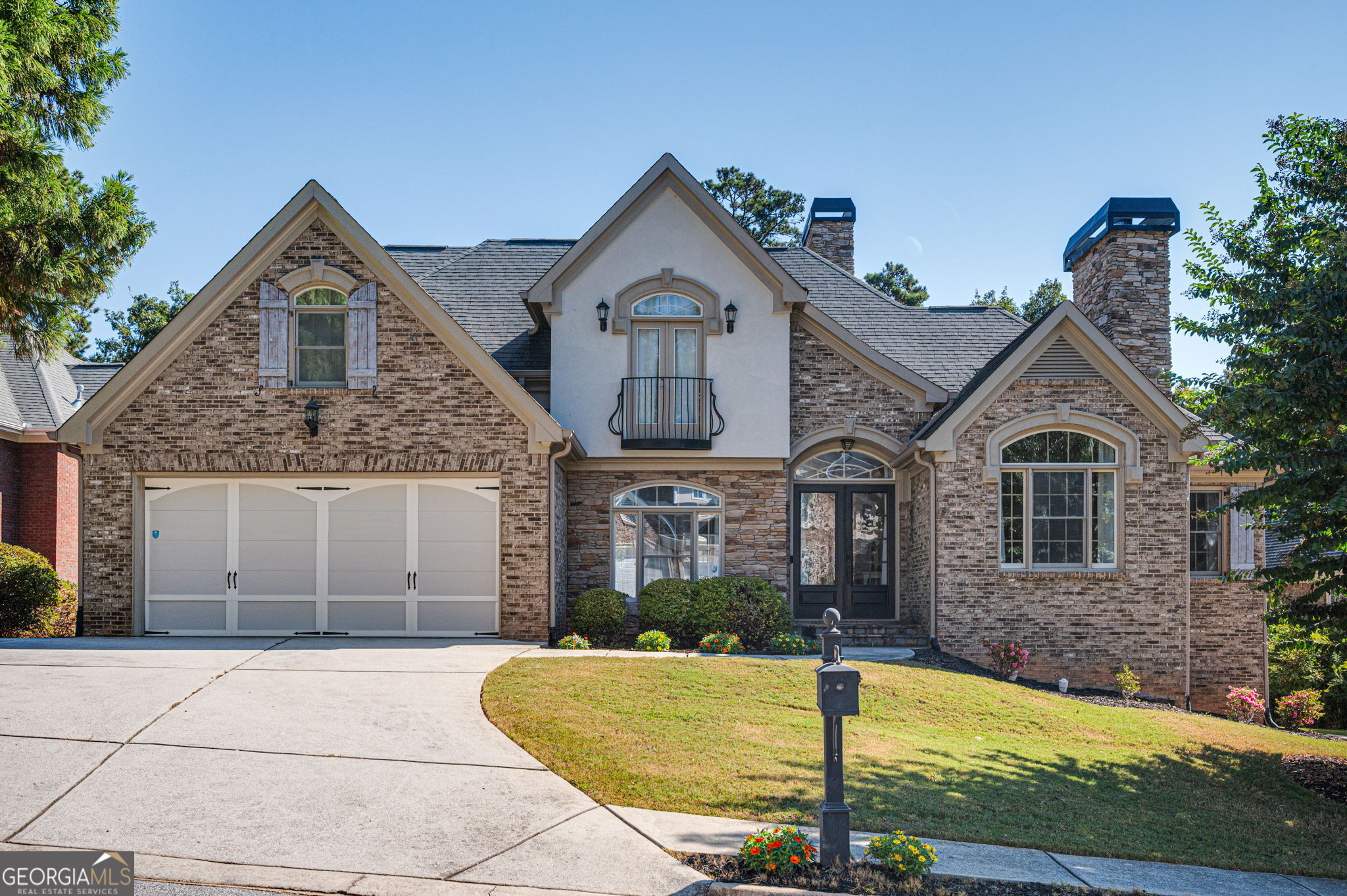 This exquisite 4 Bedroom, 2.5 Bath European-Style brick, stucco, and stone residence blends timeless elegance with striking architectural detail. With its manicured landscaping, stately facade, and welcoming presence, the home's curb appeal sets the tone for the sophistication inside and the grand double-door entry with arched transom and Juliet balcony with iron railings introduces the elegance that awaits. Once inside, the main level showcases soaring ceilings, abundant natural light, and an open concept floorplan. The oversized great room features a wall-mounted fireplace with shiplap surround and a floating wood mantle. The updated gourmet kitchen is equipped with quartz countertops, tiled backsplash, a counter-height island with seating, stainless steel appliances including a gas cooktop, wall oven, and built-in microwave. A breakfast room, formal dining room, and vaulted office with marble fireplace, built-ins, and French doors add both function and refinement. The spacious master suite offers his-and-hers closets and an updated spa-like bath with dual vanity, soaking tub, and a massive tiled shower. A half bath and mudroom complete the main level. Upstairs, three generously sized bedrooms share a well-appointed tiled hall bath with double vanity. Additional highlights include a two-car garage and a full unfinished basement with endless possibilities for future expansion. The exterior is equally impressive with a large deck and lower-level patio that overlook the backyard and provide picturesque views of the signature Par 3 #6 hole at Ashton Hills Golf Club. Perfectly located, this home is just a short walk or golf cart ride to the Covington Square and minutes from I-20, Piedmont Newton Hospital, shopping, dining, and entertainment.